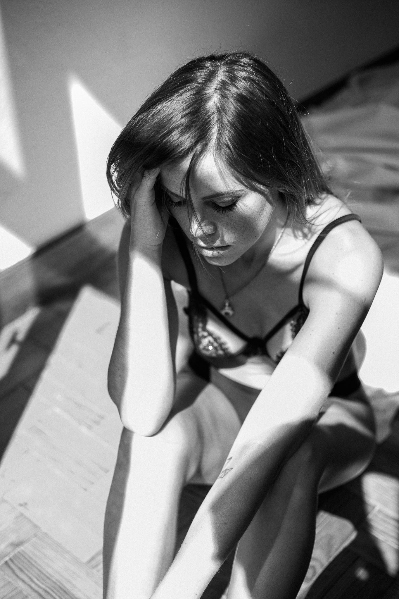 A series of black and white artistic photographs showing a person in contemplative poses with dramatic lighting and shadows.