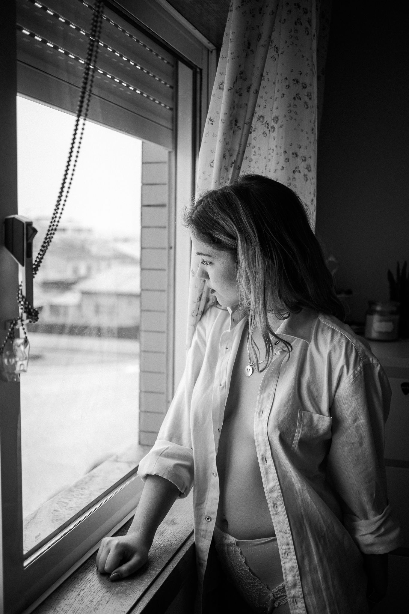 A series of black and white photographs showing someone gazing thoughtfully through a window in different poses.