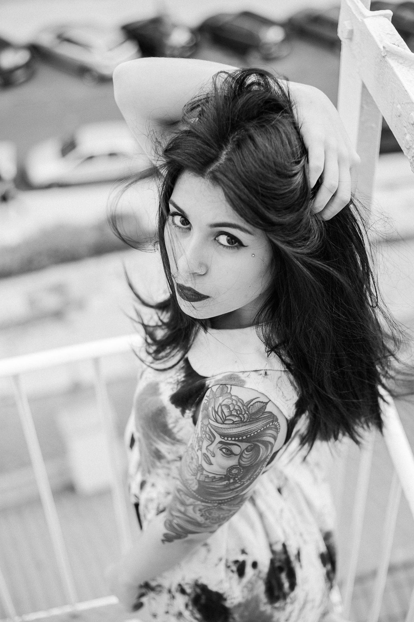 Black and white artistic portrait series showing tattoos and dramatic poses against a white railing background.