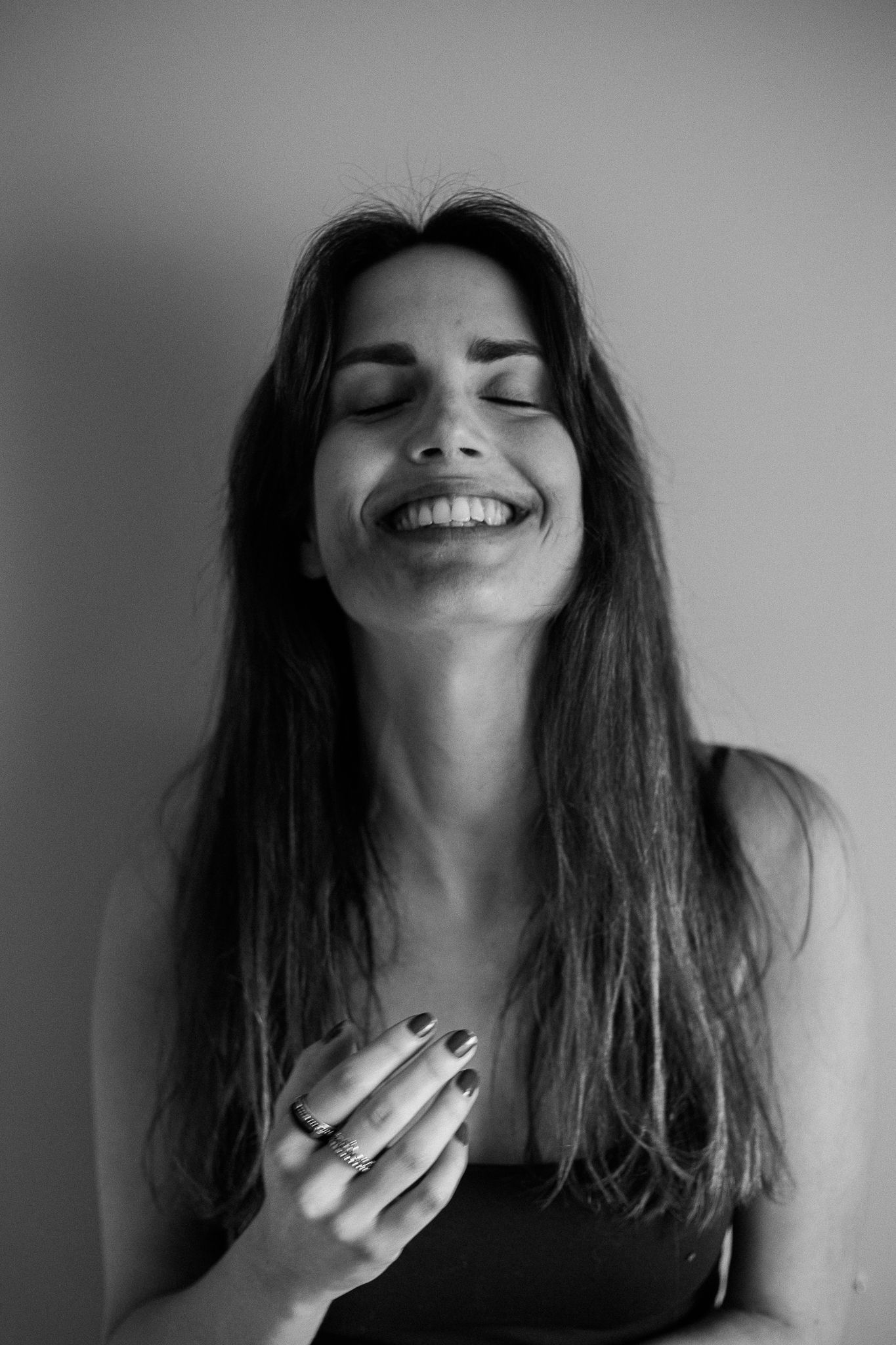 Black and white photo series showing expressions of joy and laughter with closed eyes and dark hair.