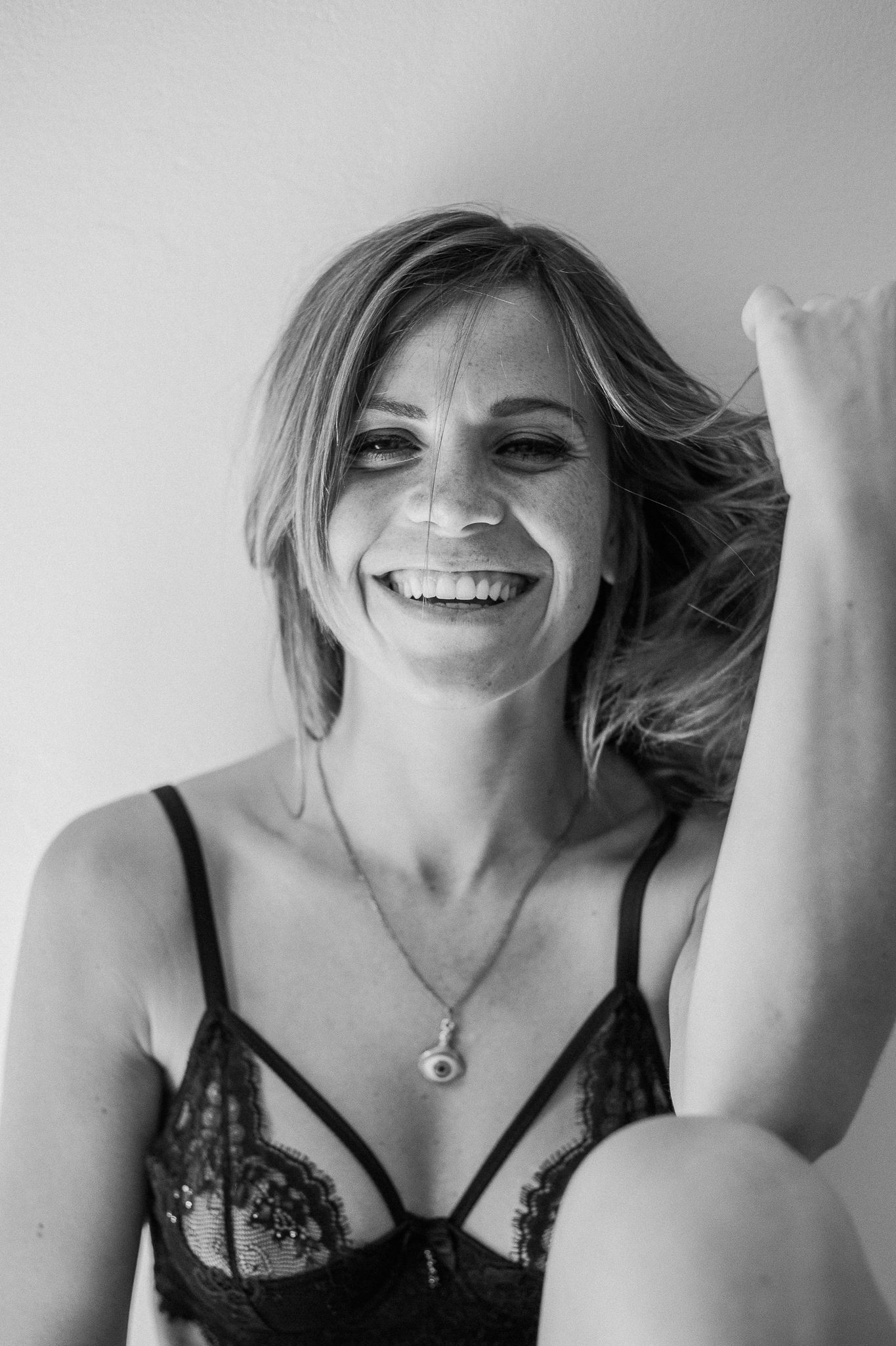 A series of black and white portraits showing a person wearing a lace bra while smiling and posing playfully.