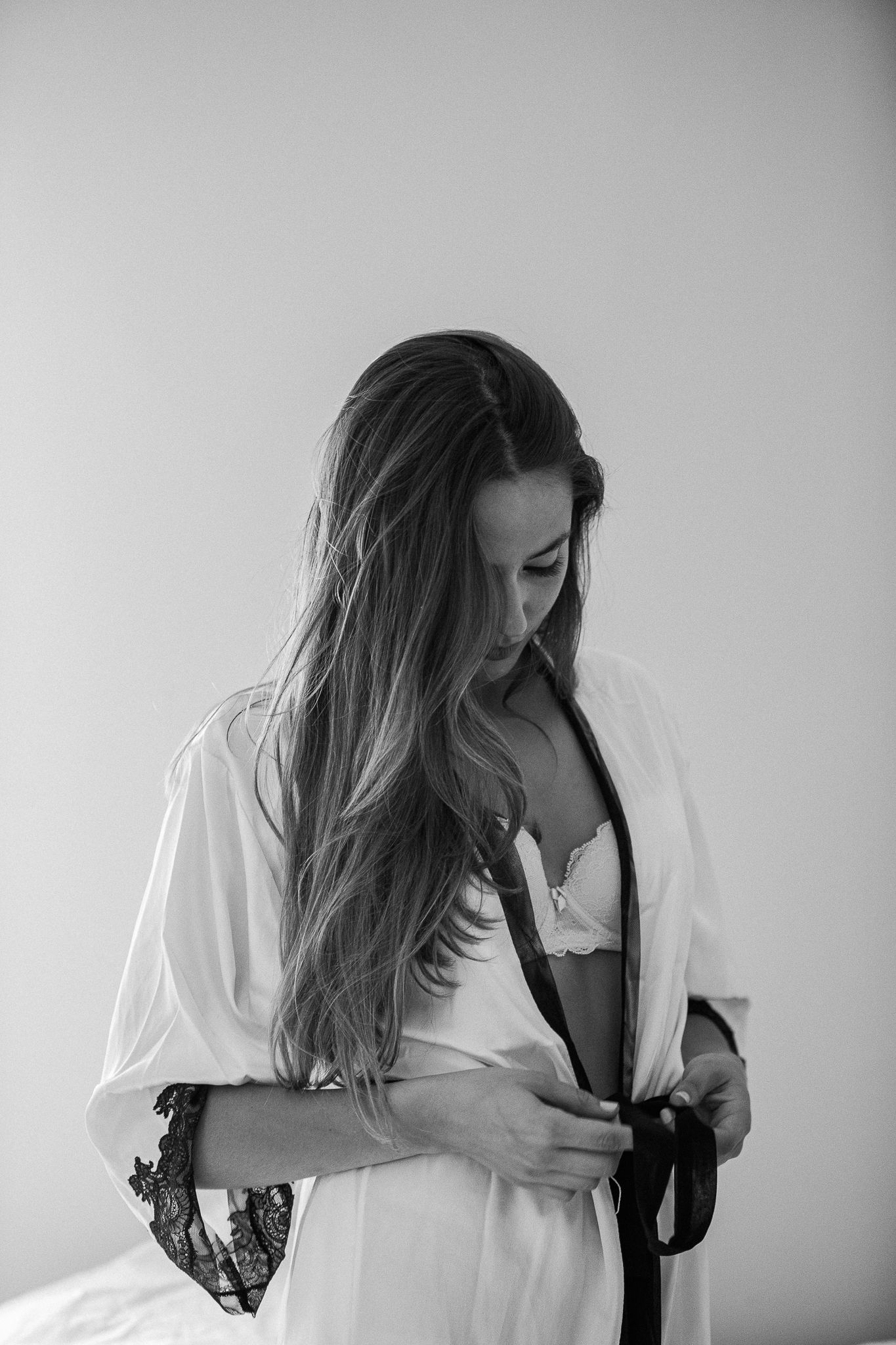 A series of artistic black and white boudoir photos showing a figure in white clothing against a light background.