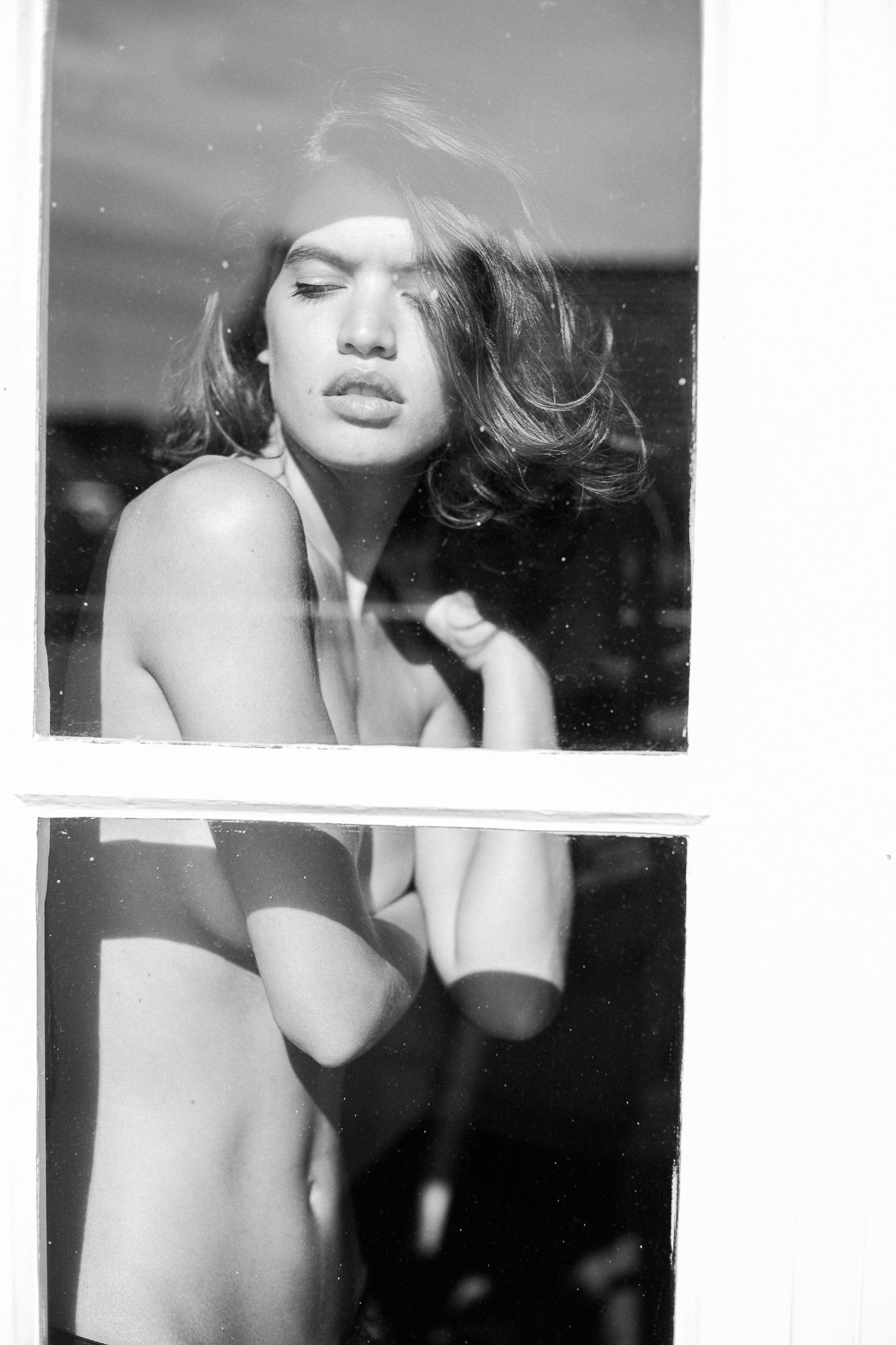 Artistic black and white fashion photograph showing dramatic lighting and windswept hair in a glamorous portrait style.