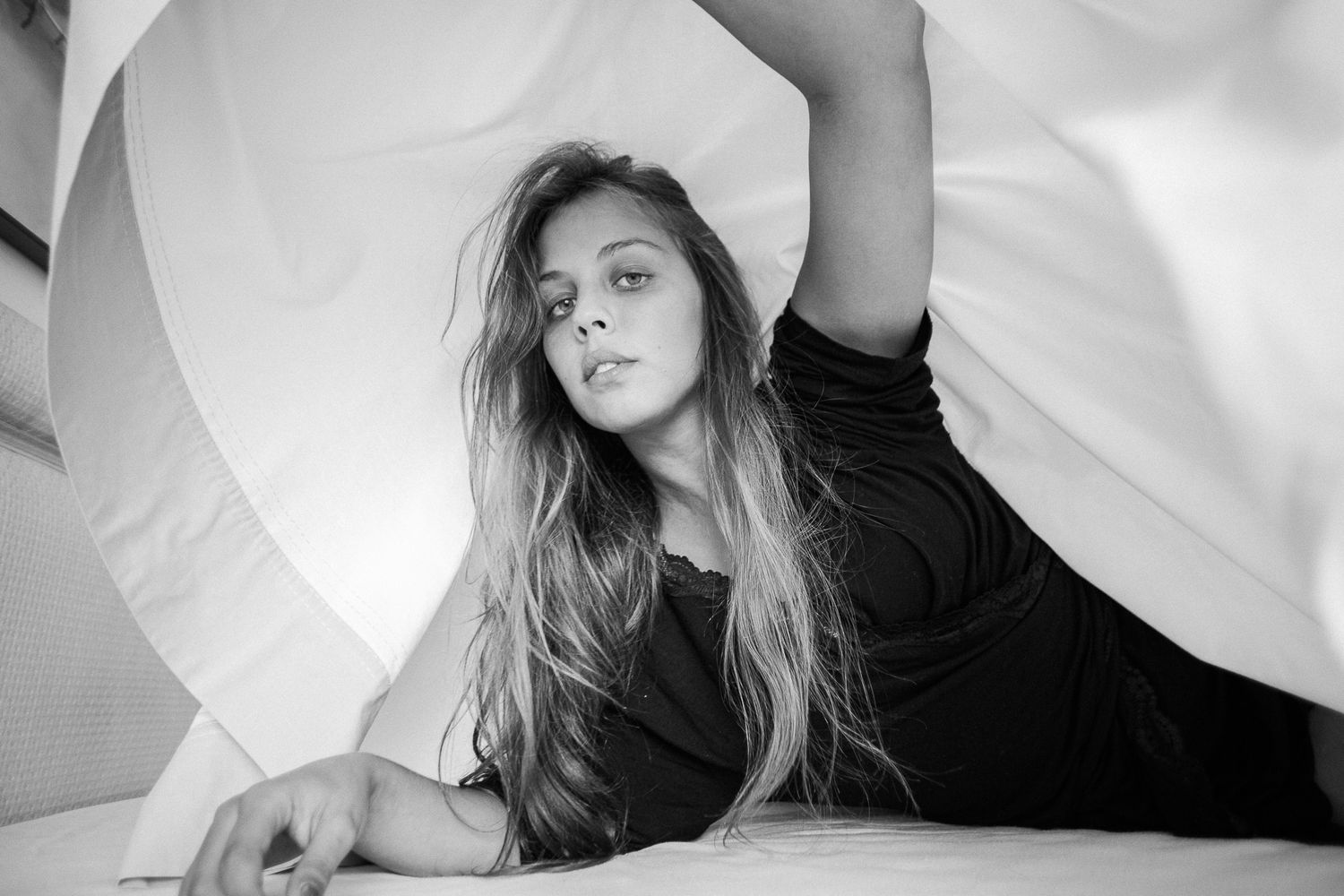 A series of black and white artistic portraits showing movement and flowing fabric in a studio setting.