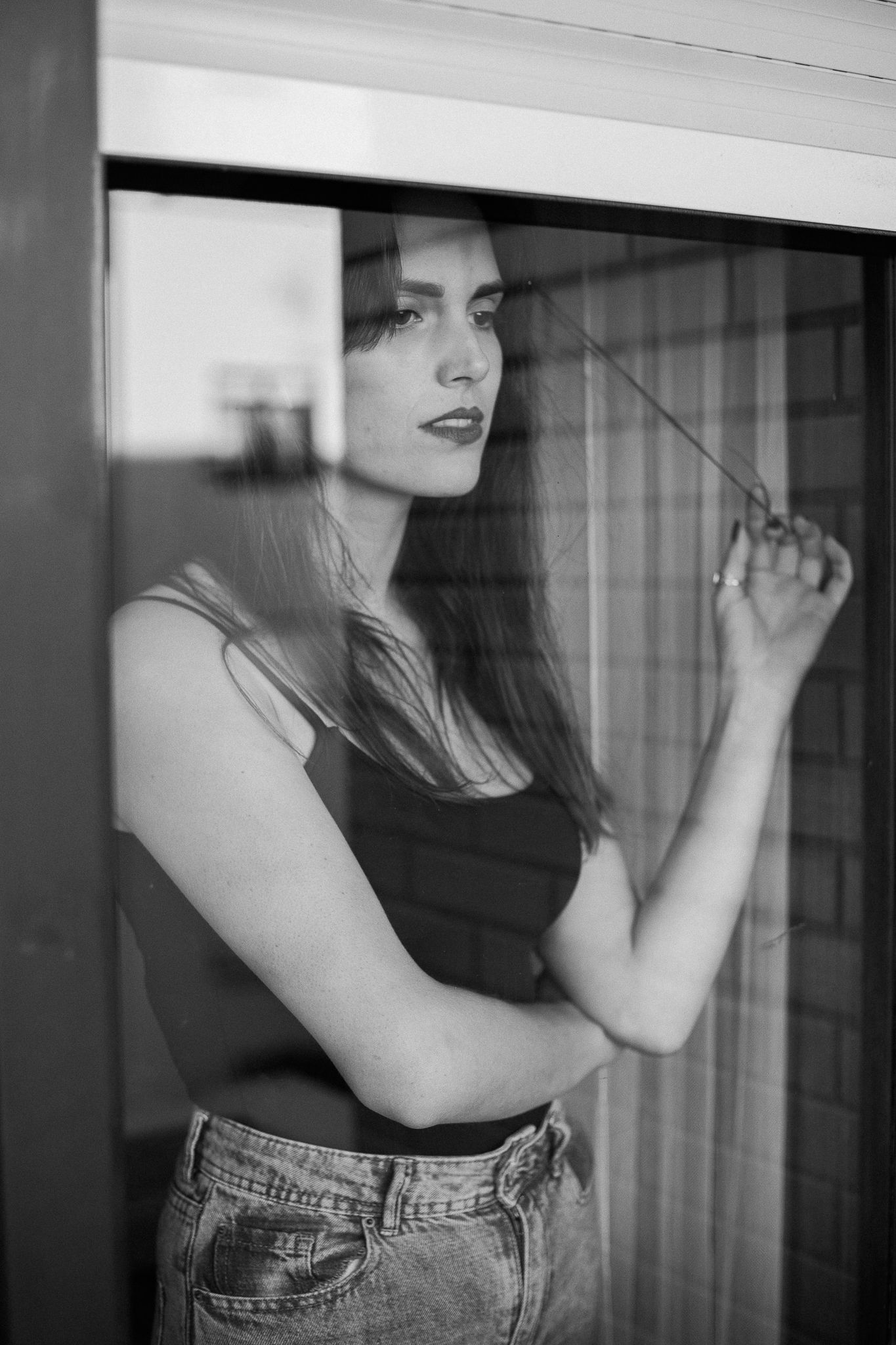 Moody black and white fashion photos featuring casual denim and tank top styling against window light.