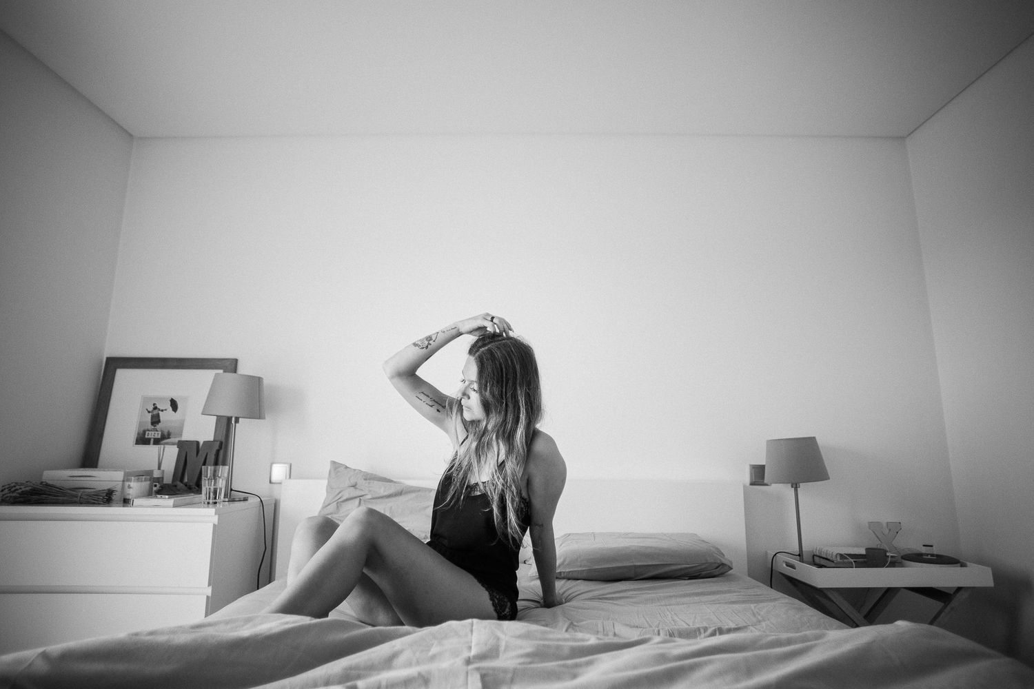Monochrome photograph of a bedroom scene with soft natural lighting.