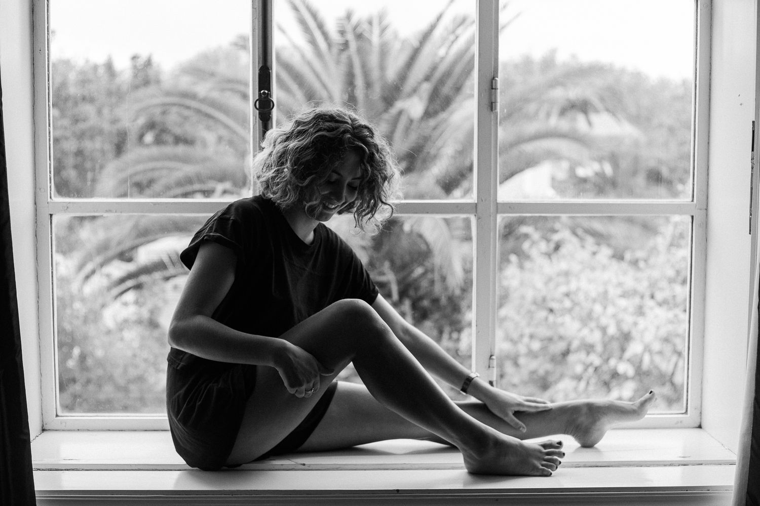 A person sits in silhouette by a window with a guitar, creating a moody artistic composition against natural light.