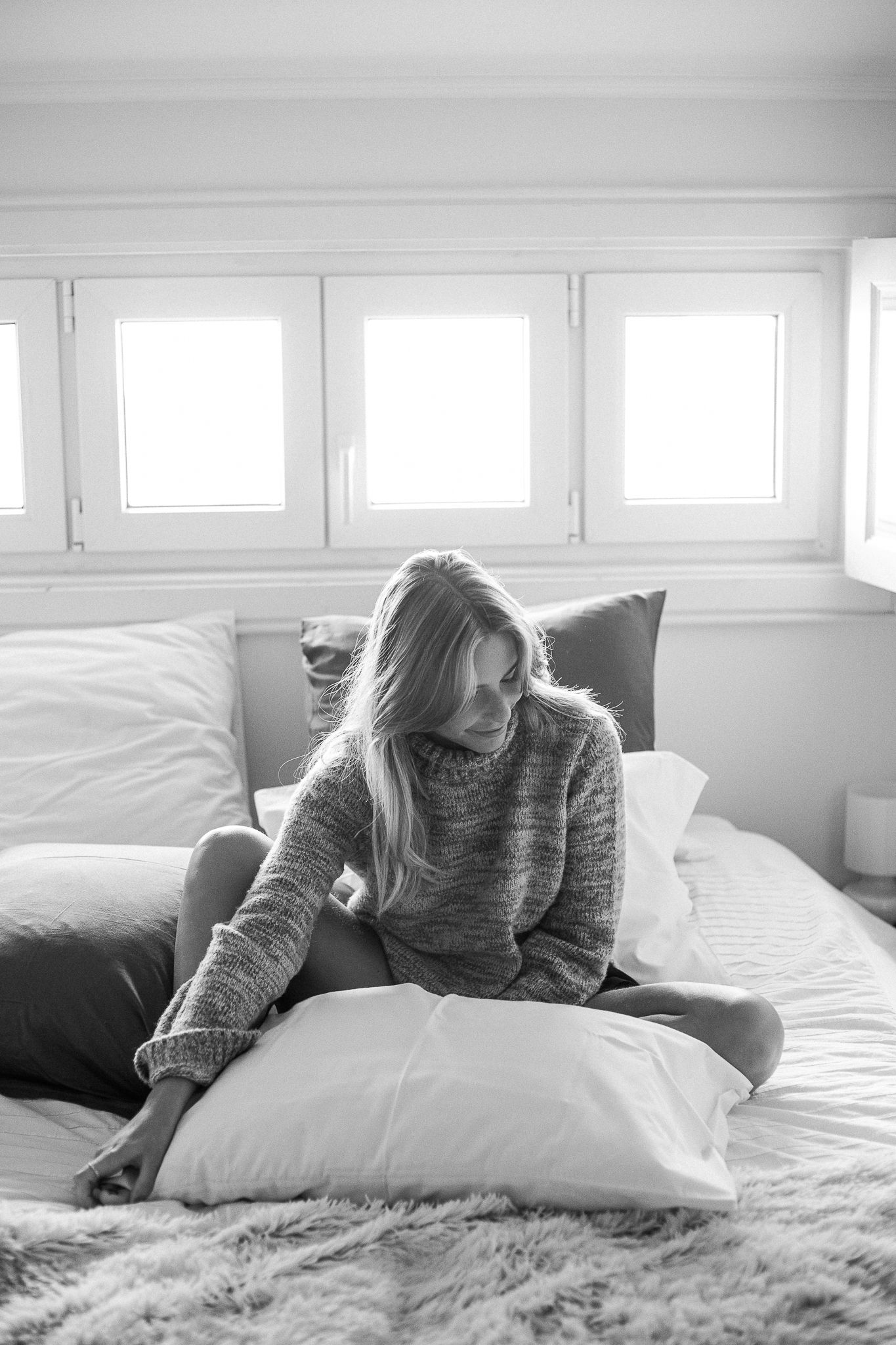 Black and white photo sequence of someone lying comfortably on a bed with white pillows and natural light.