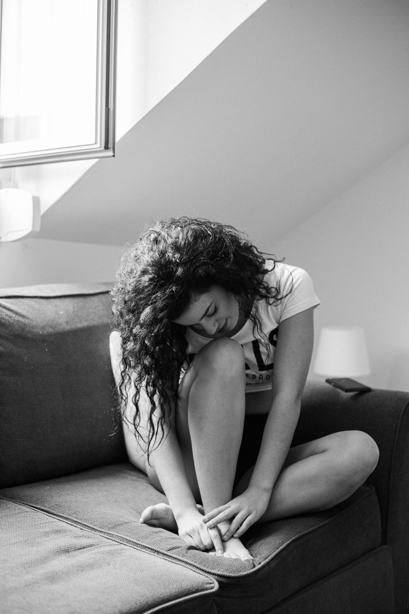 Moody monochrome series showing someone in athletic wear sitting on a sofa in different contemplative poses.