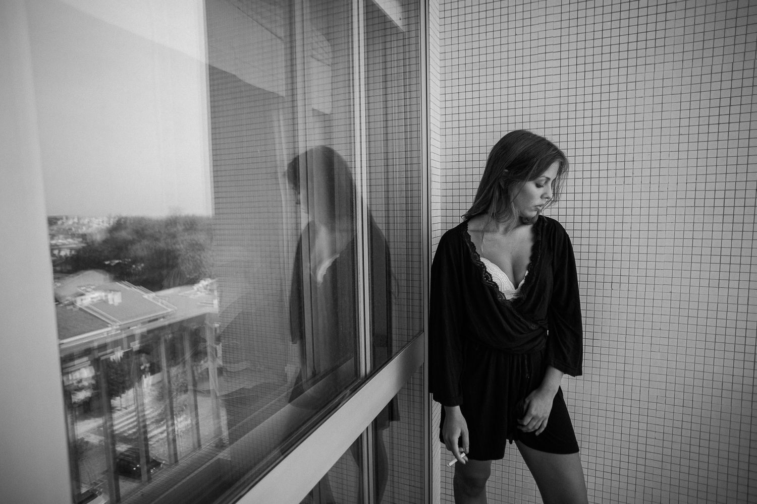 A series of black and white photographs showing someone walking through a hallway with tiled walls.
