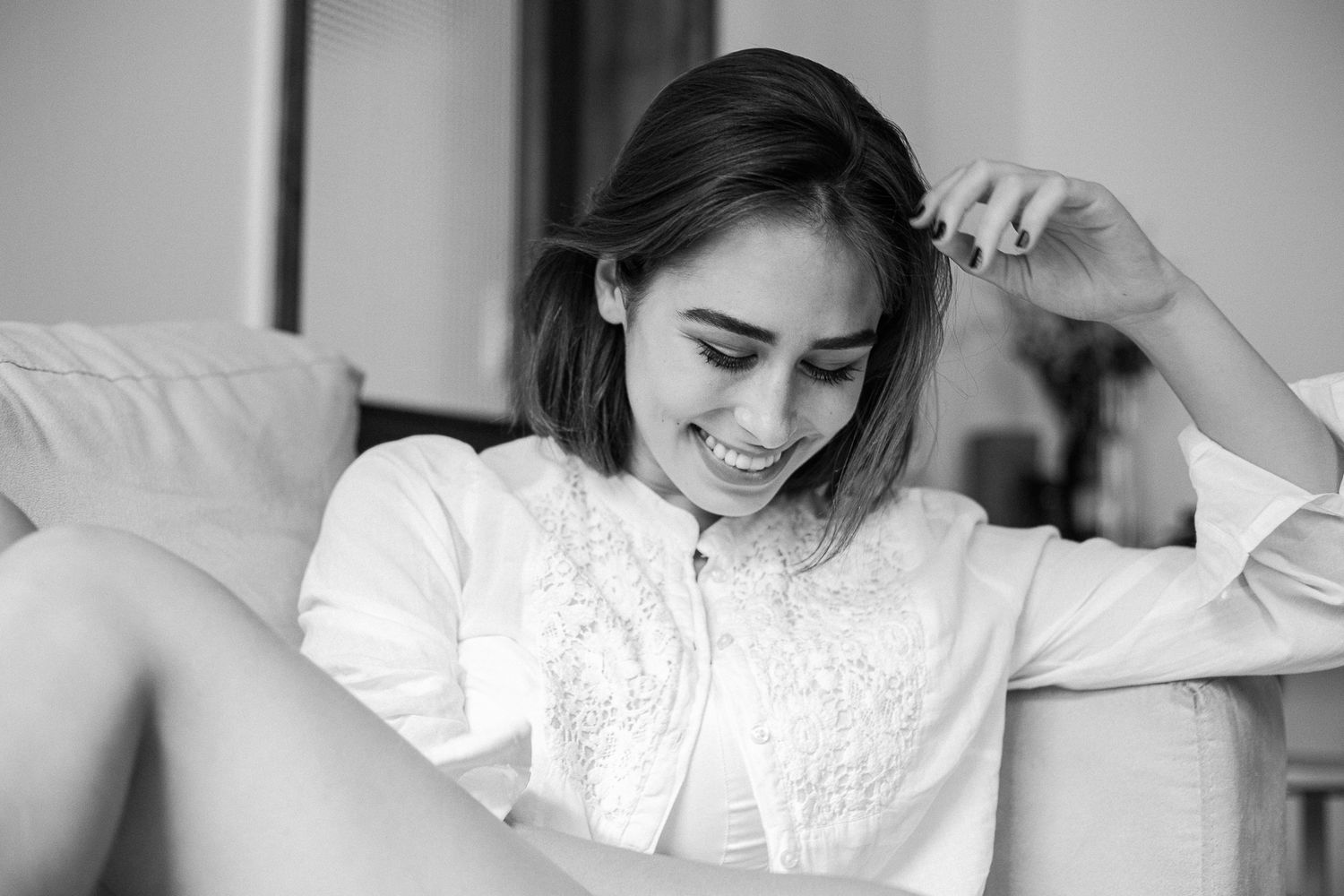 Black and white photo series showing someone in a white blouse relaxing on a couch in different casual poses.
