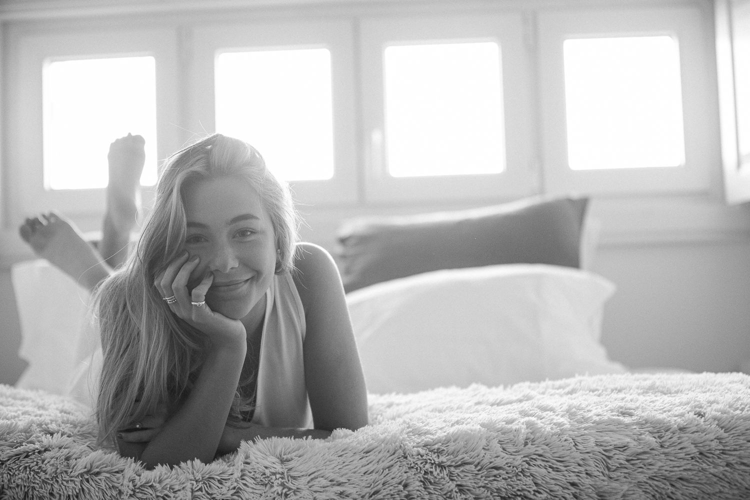 A black and white photo series showing someone lying on a bed in various relaxed poses.