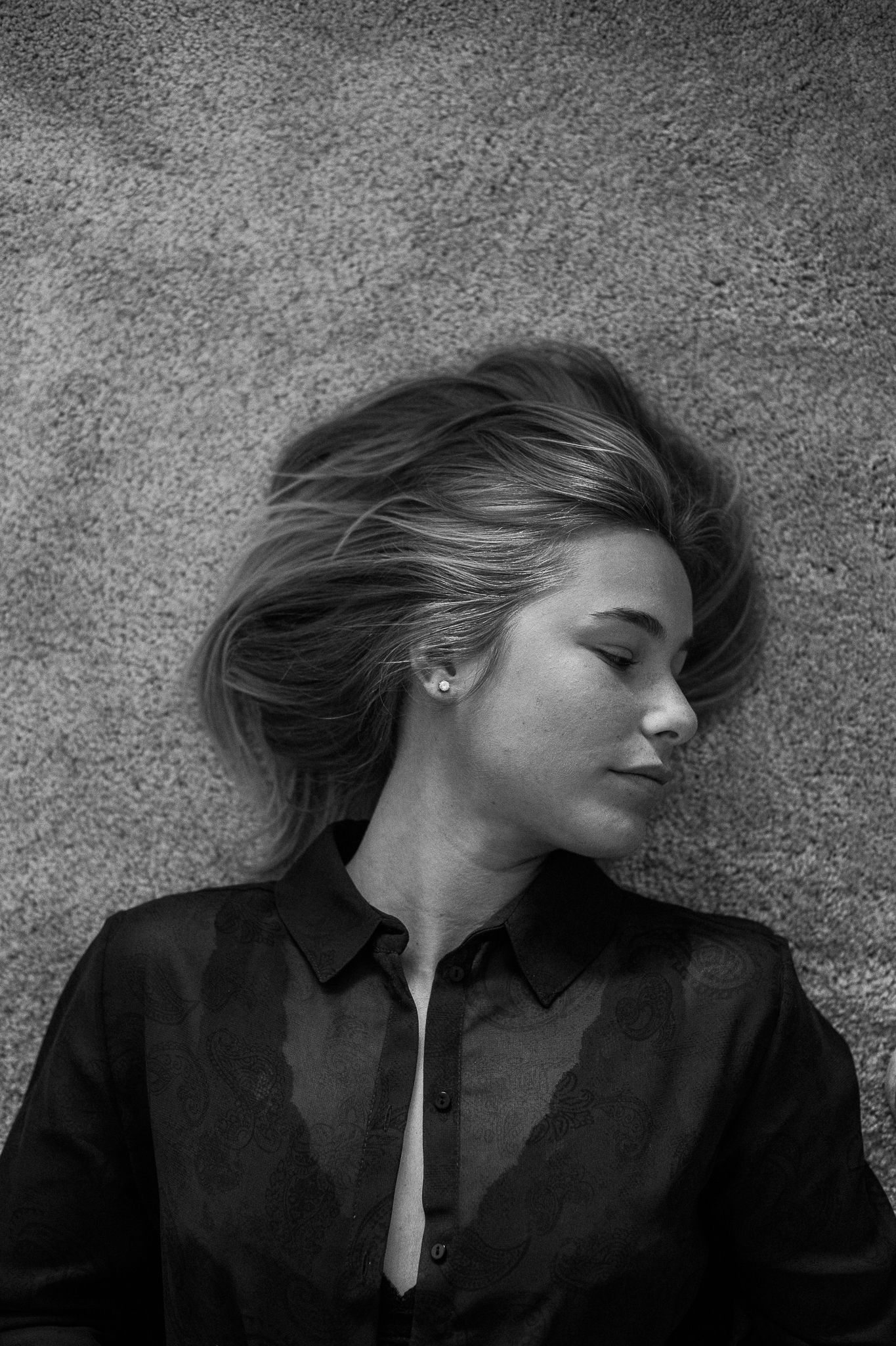 Dramatic black and white sequence of a person lying down with flowing hair against a textured surface.
