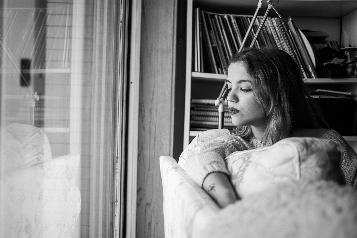 Black and white photo series showing a person resting on a couch near a window in different poses.