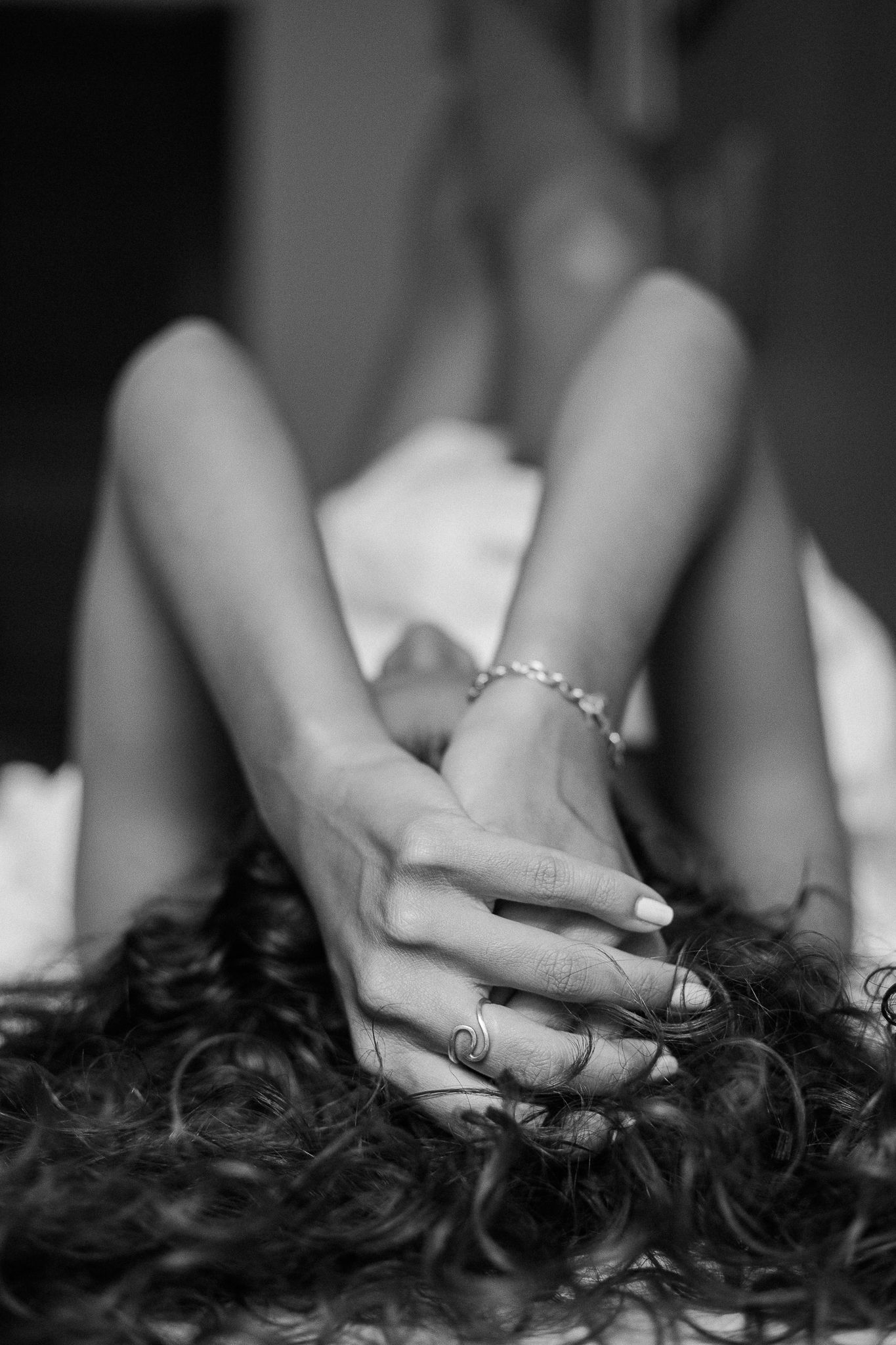 Hands gently run through dark curly hair in a series of black and white artistic photographs.