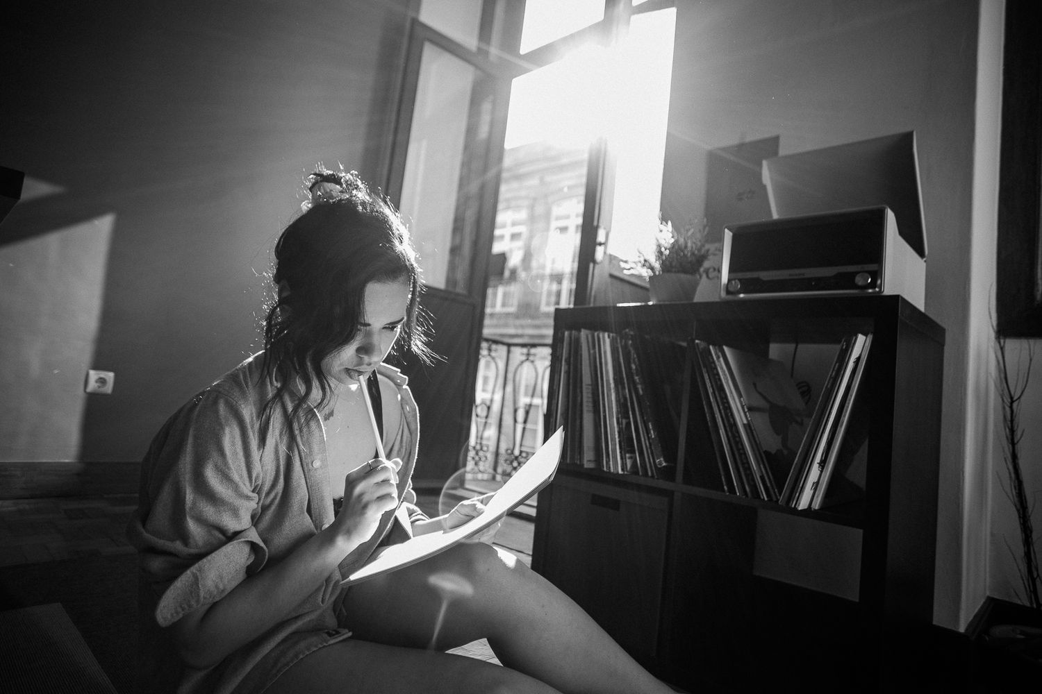 Moody indoor scene with dramatic shadows and bookshelves in the background.