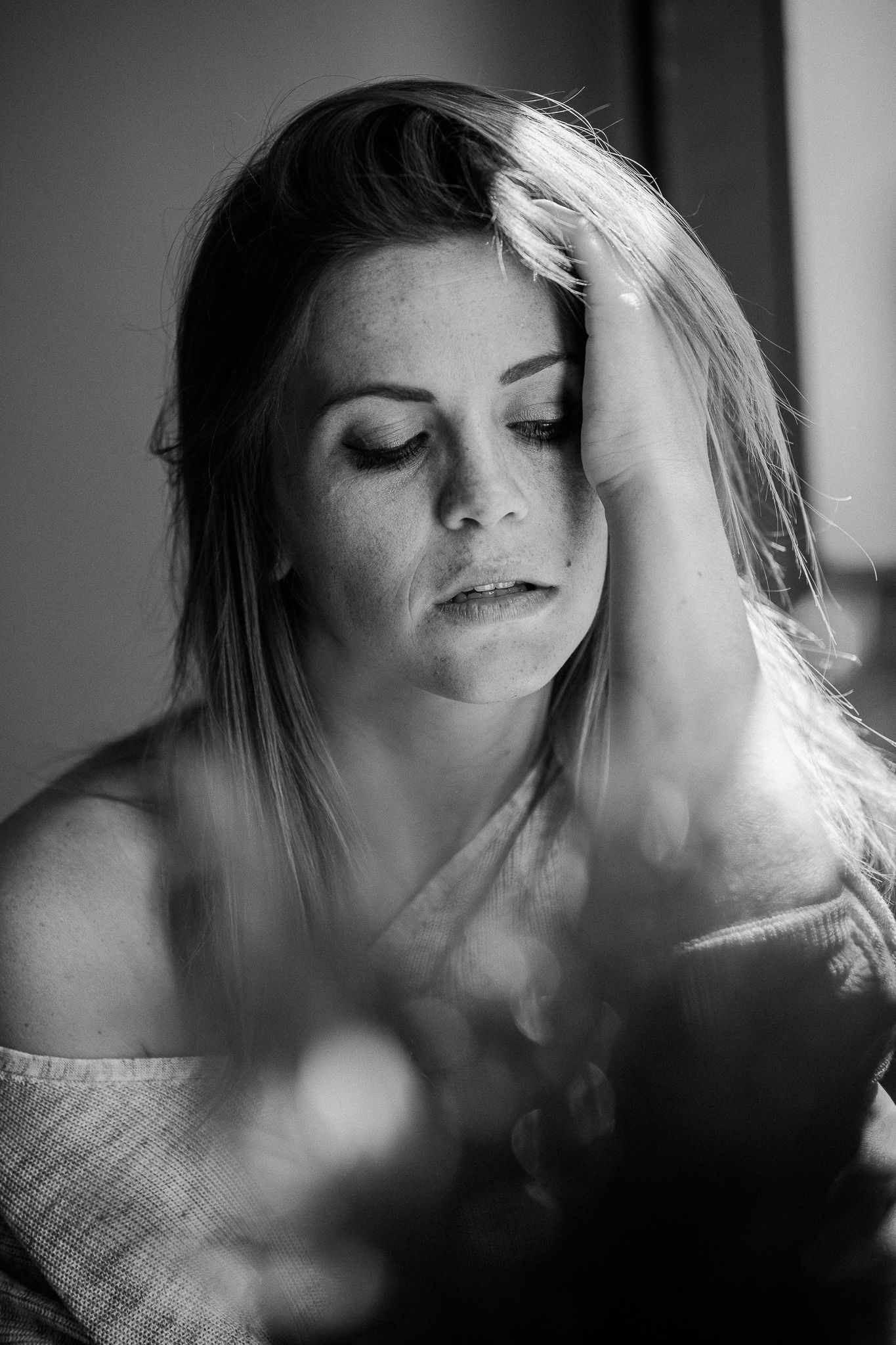 Black and white portrait of a woman with closed eyes in dramatic lighting with soft focus and natural pose.