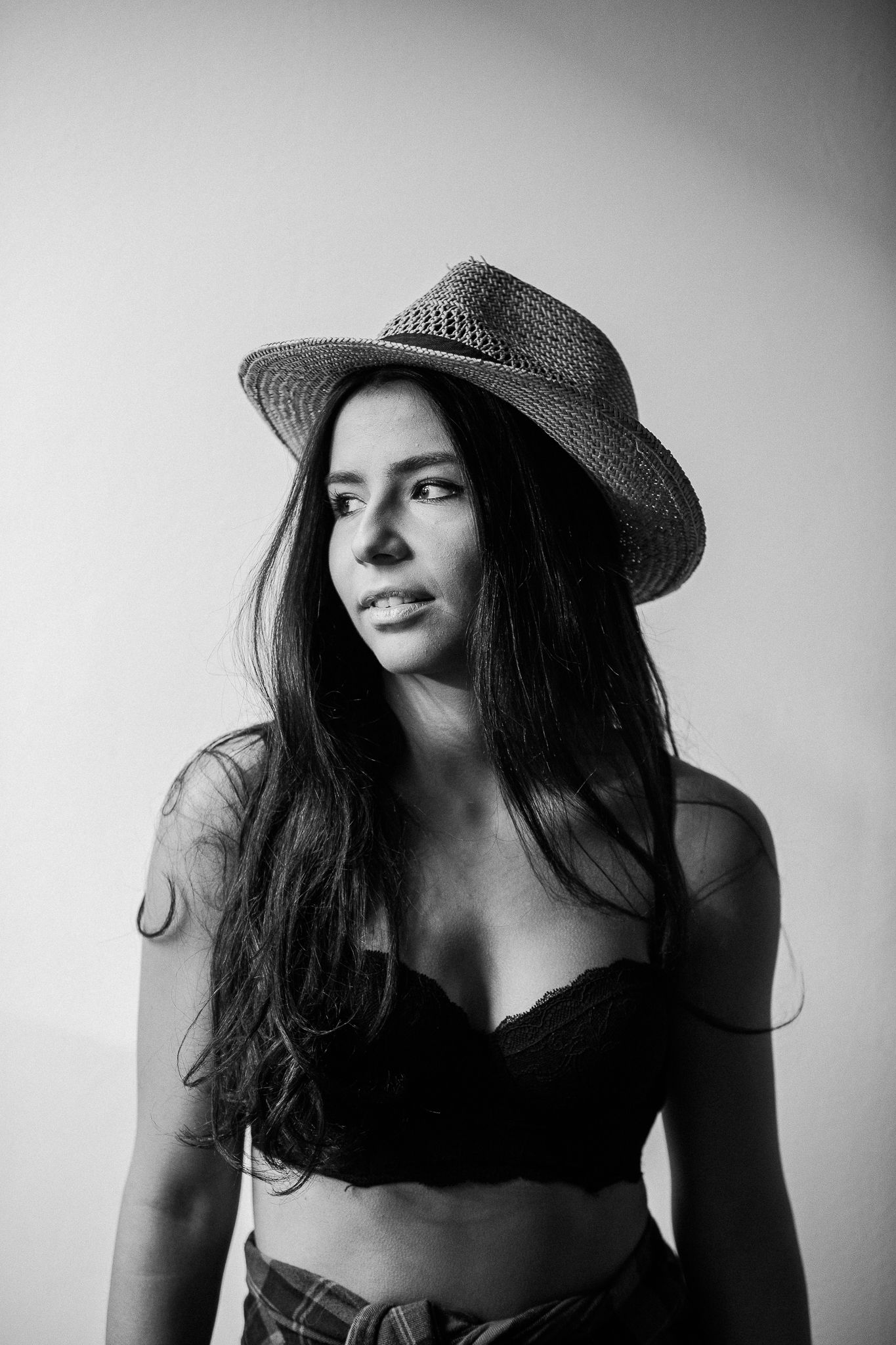 Artistic black and white portrait of a woman in a hat creating dramatic shadows and contrasts.