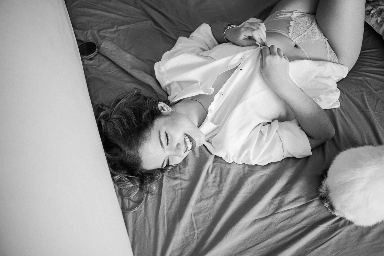 A person lies relaxed on bedding in black and white, wearing a light colored shirt while resting.