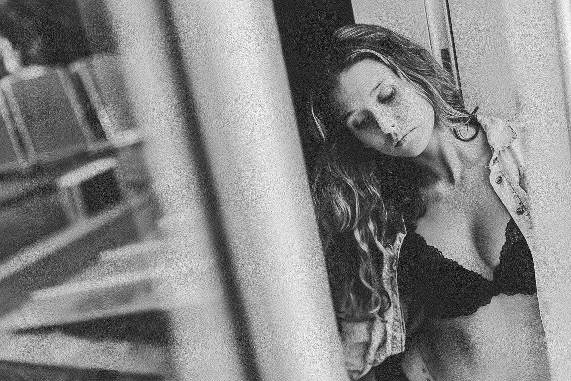 A black and white fashion photoshoot with a woman posing elegantly between architectural columns.
