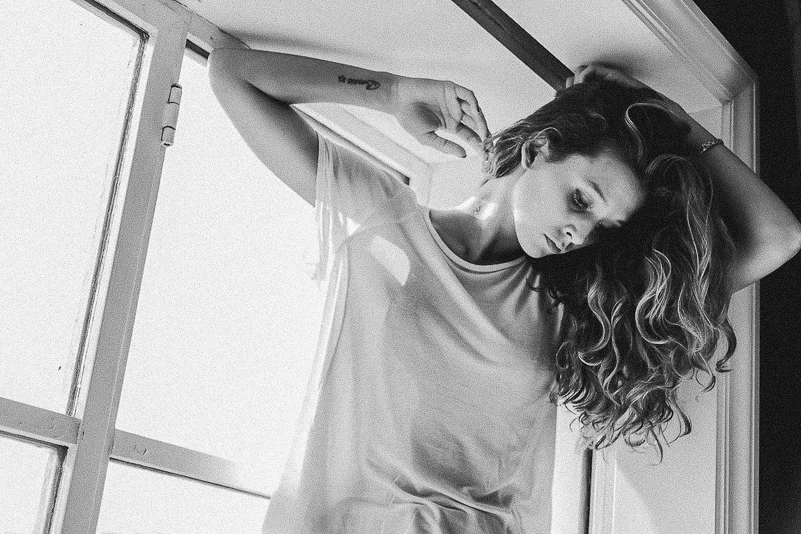 A series of black and white photos showing a person in casual clothing posing against a bright window background.
