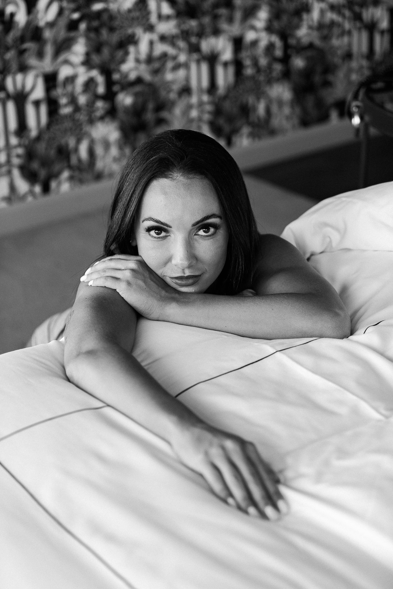 Black and white portrait series showing intimate bedroom poses with white sheets.
