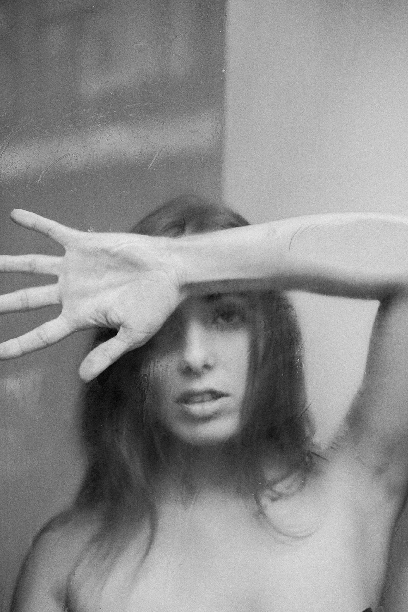 Ethereal black and white portrait with hand gestures creating dramatic shadows.