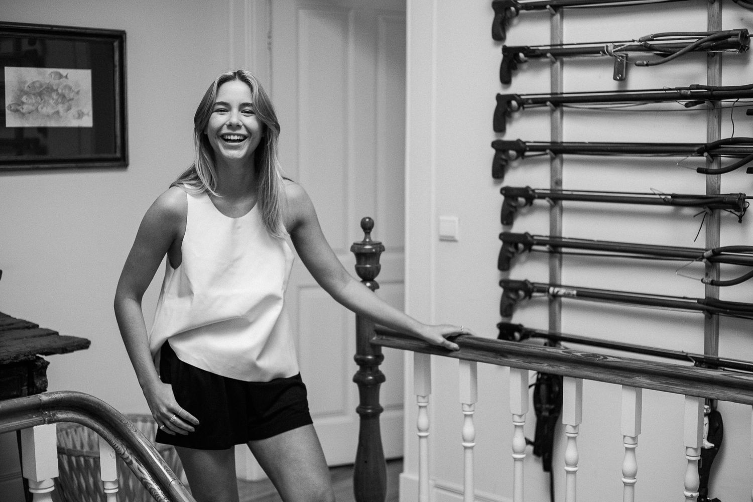 A series of black and white photos showing a dancer practicing ballet moves at a ballet barre in a dance studio.