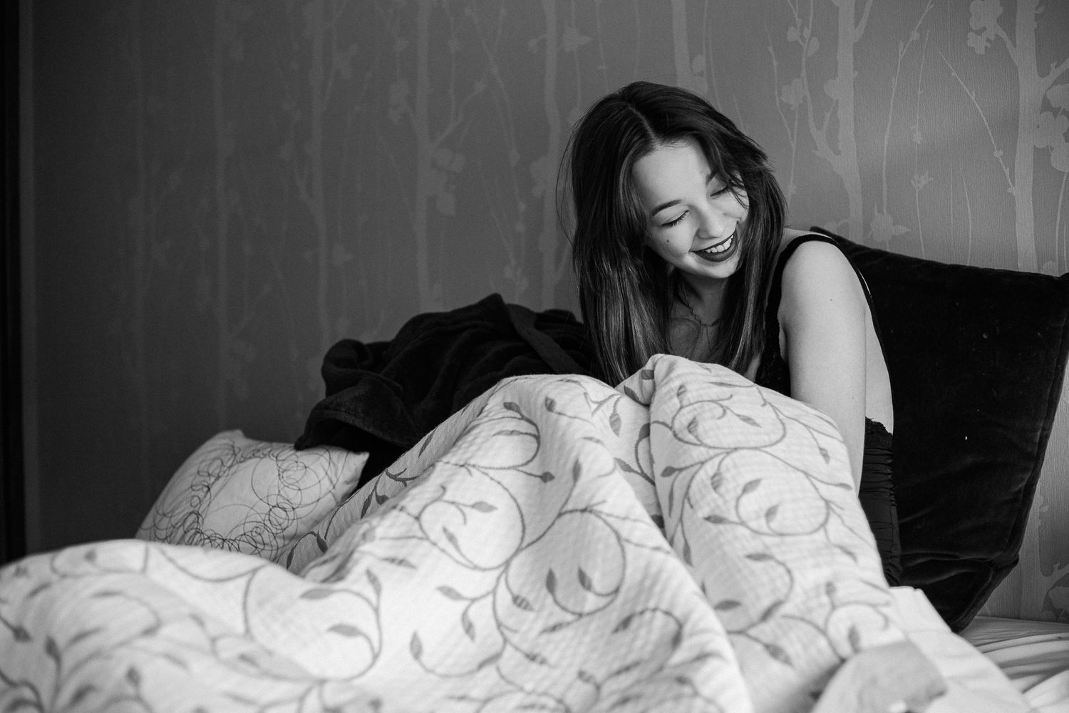 Artistic bedroom photoshoot with decorative wallpaper and white bedding.