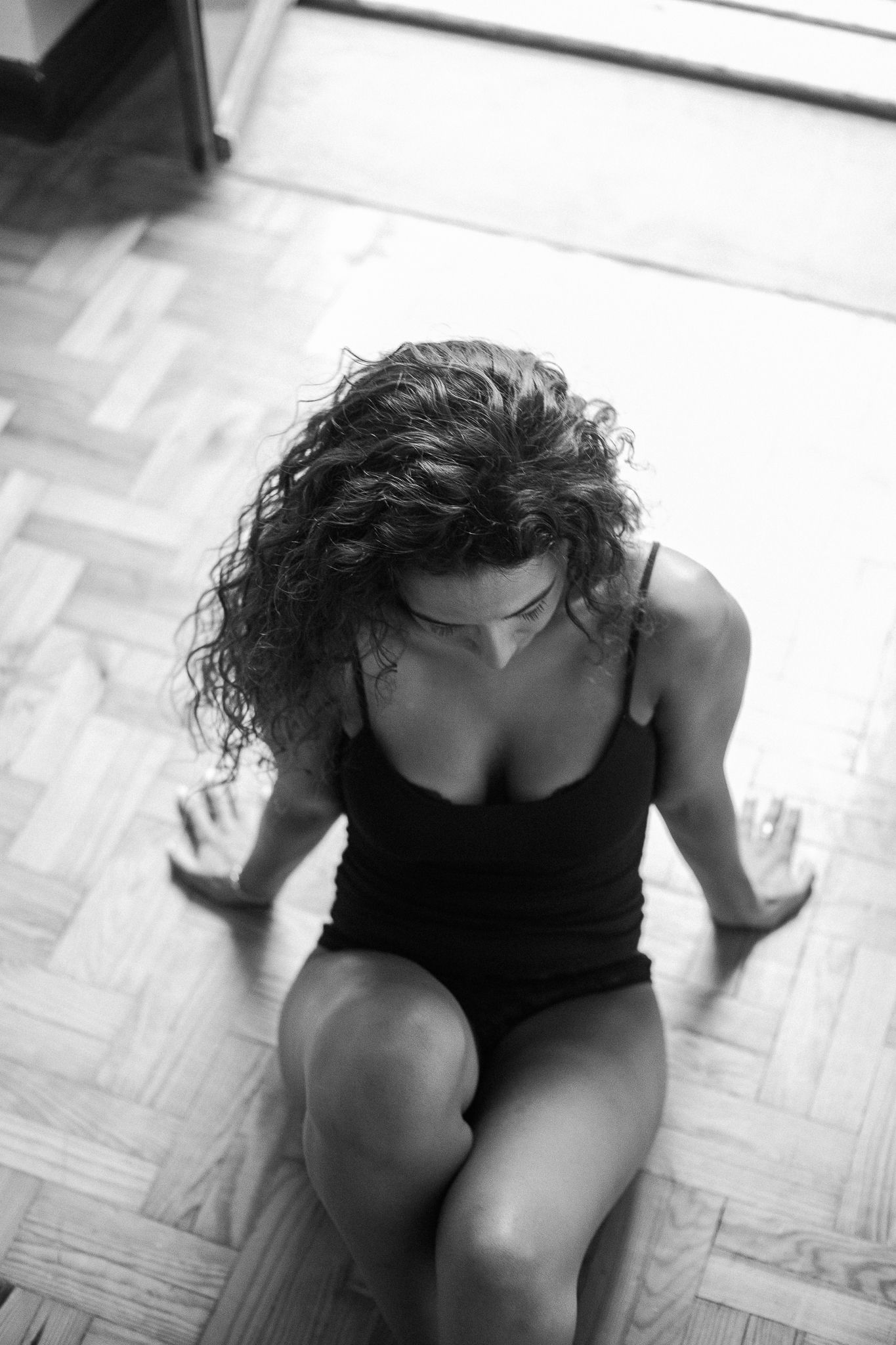 A black and white photo sequence shows a person in dark clothing crouching down on a hardwood floor.