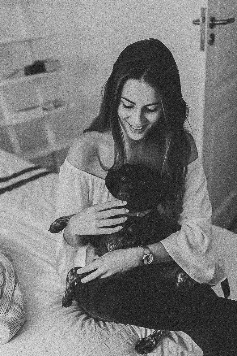 A series of intimate black and white photographs showing someone playing with a black cat on a bed.