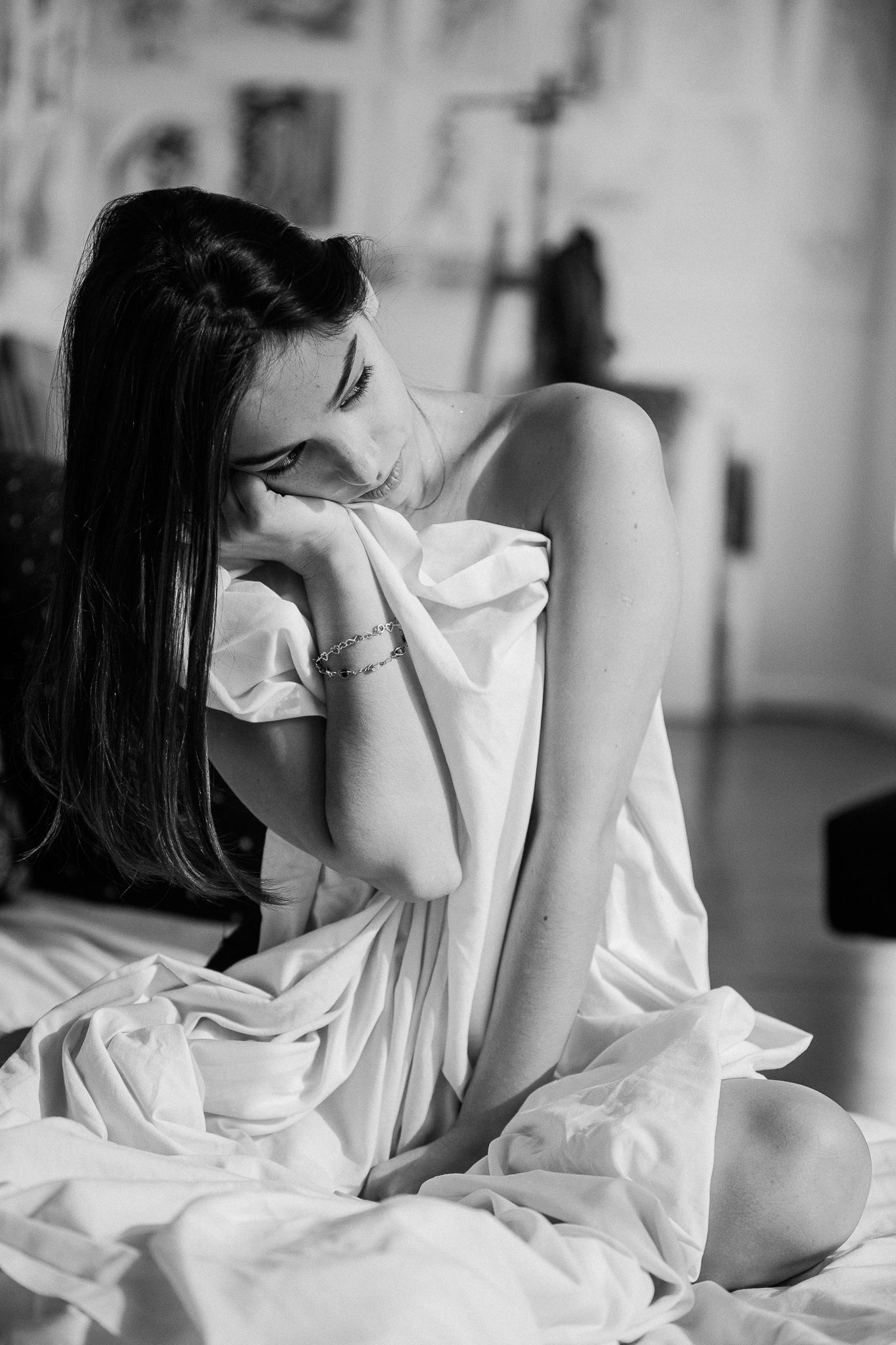 A series of black and white photos showing a person lying in bed with white sheets covering their face.