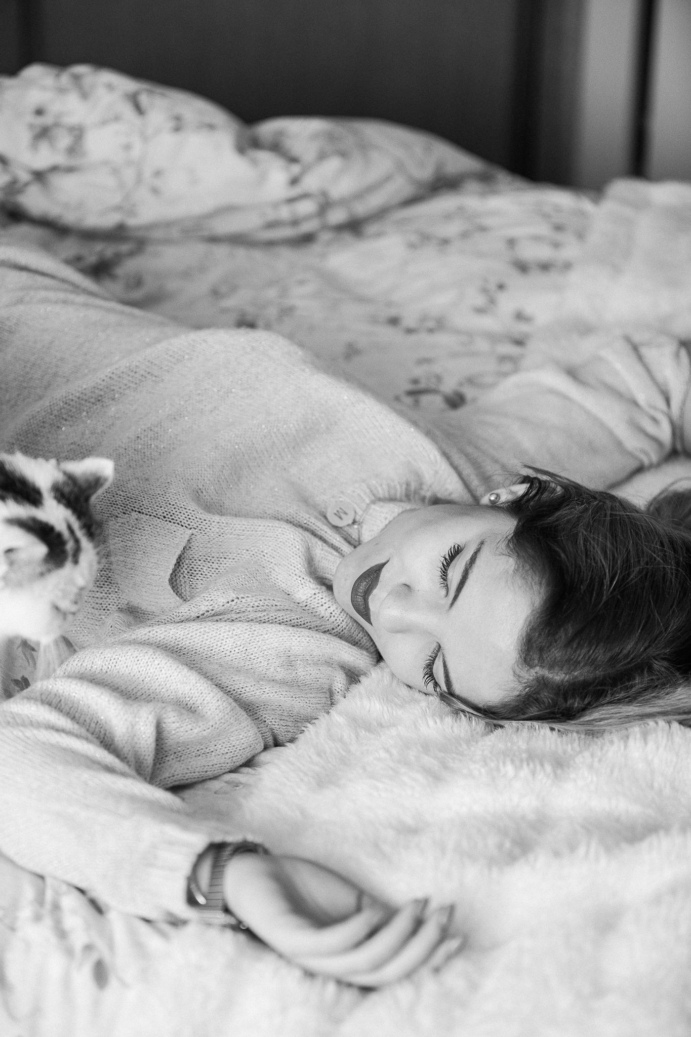 A black and white photo shows someone resting peacefully on white bedding with soft lighting and dreamy atmosphere.