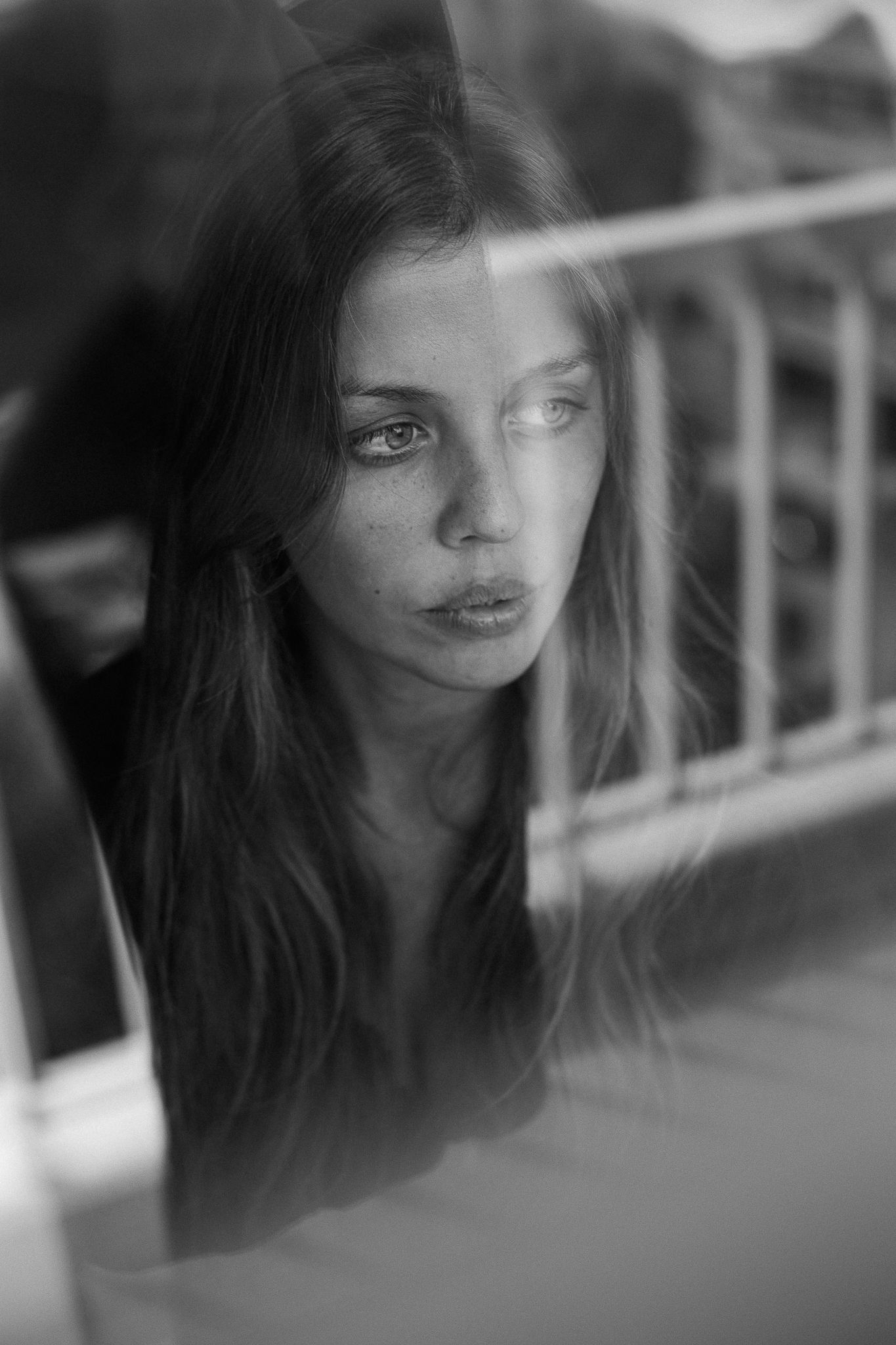 A series of black and white portraits showing a figure with dark hair in soft focus through glass or reflective surfaces.