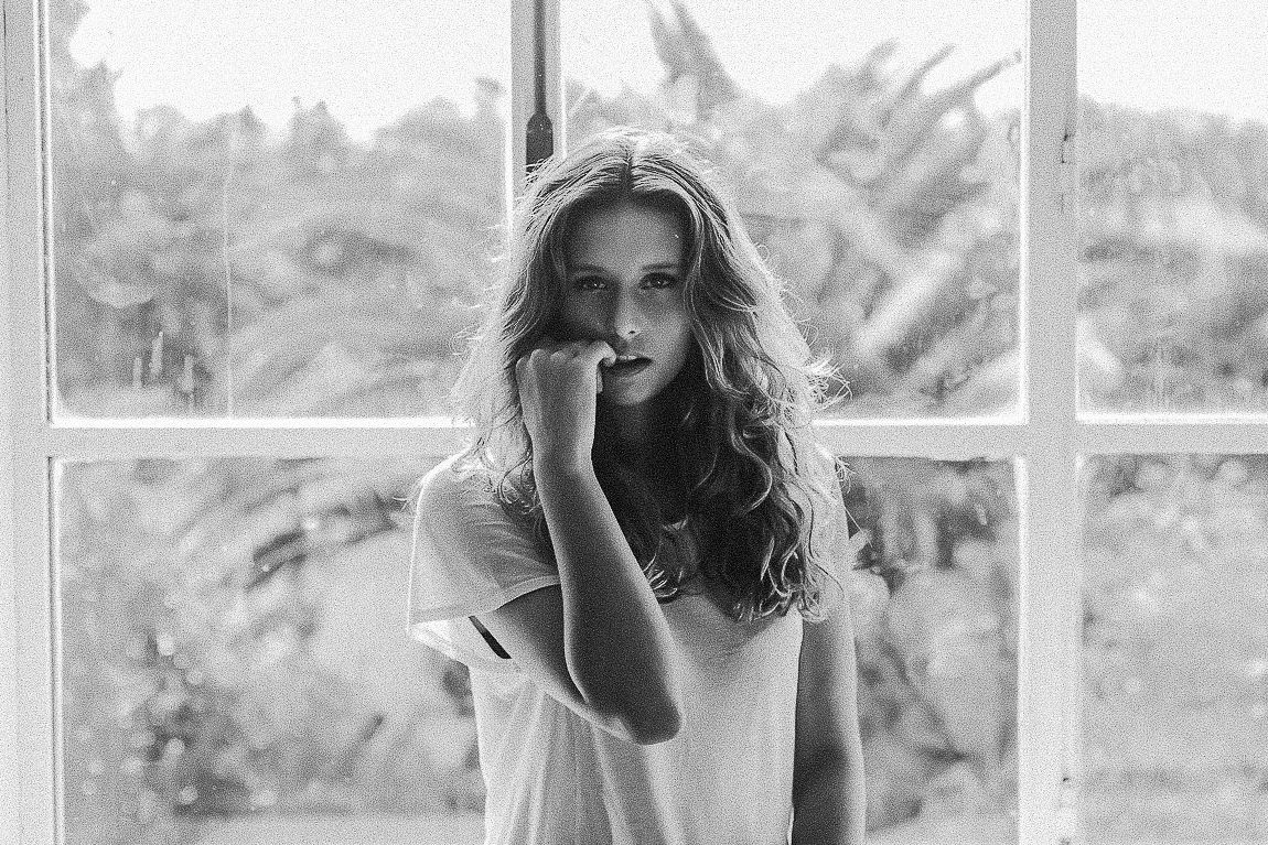 Black and white photo series showing a person in various candid poses near a window.