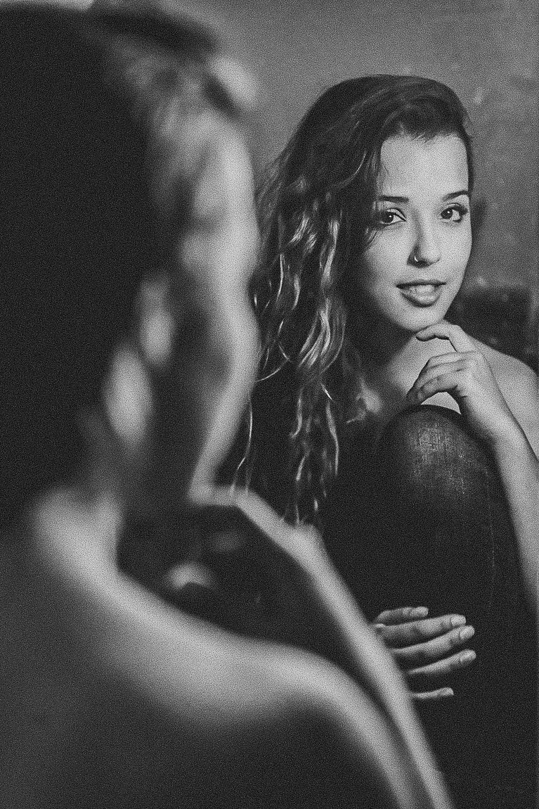 Black and white portrait of a woman with wavy hair in dramatic lighting gazing thoughtfully.