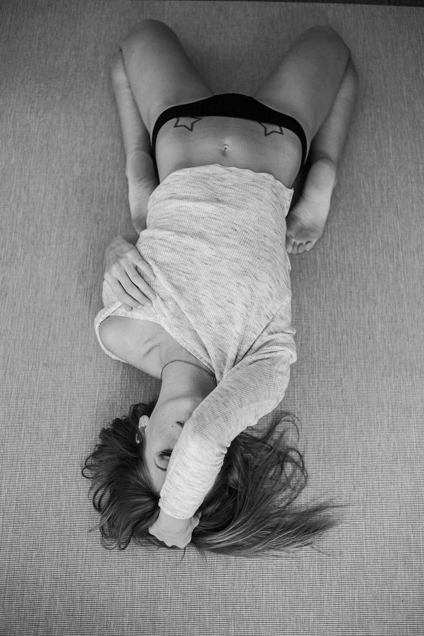 Black and white artistic portrait series showing someone lying on textured fabric in multiple poses.