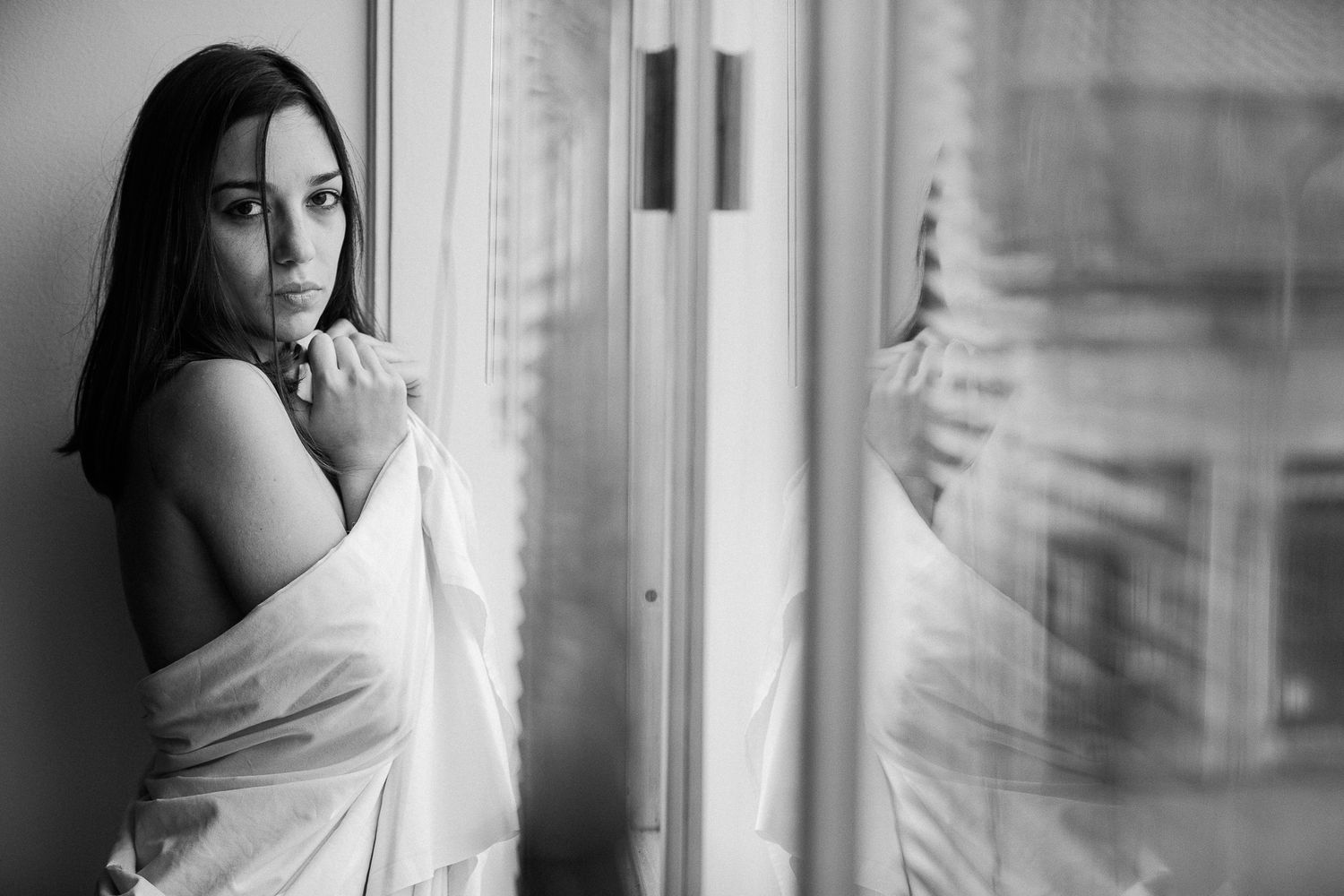 A series of monochrome portraits showing someone in white fabric near a window with dramatic lighting and shadows.