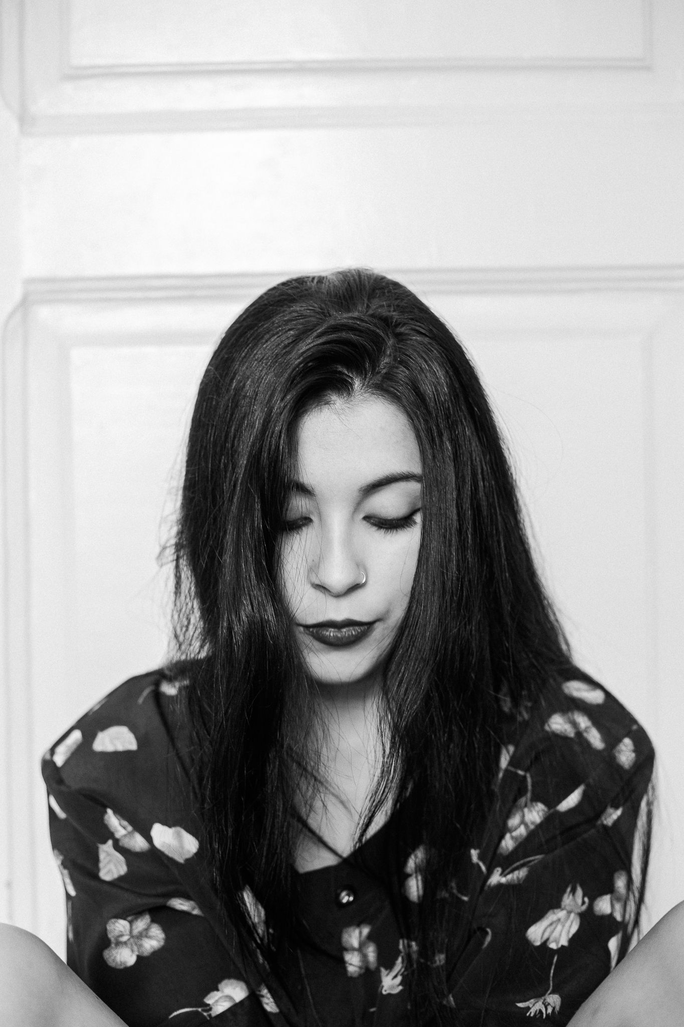 A series of artistic black and white portraits showing a person in a floral print top with dark hair looking down.
