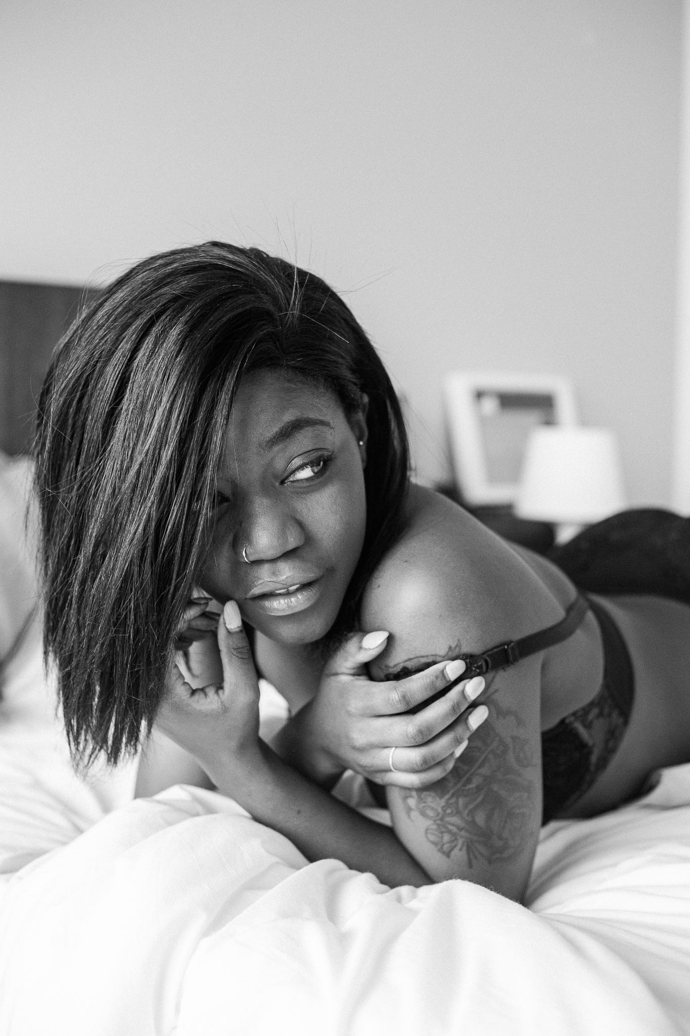 A black and white photo series showing intimate moments of a couple sharing tender embraces on white bedding.