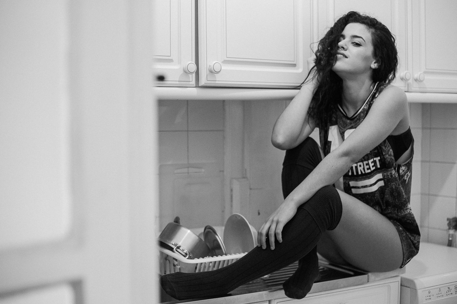 A person sits in a bathtub wearing a black dress while using a mobile phone in a black and white photo series.
