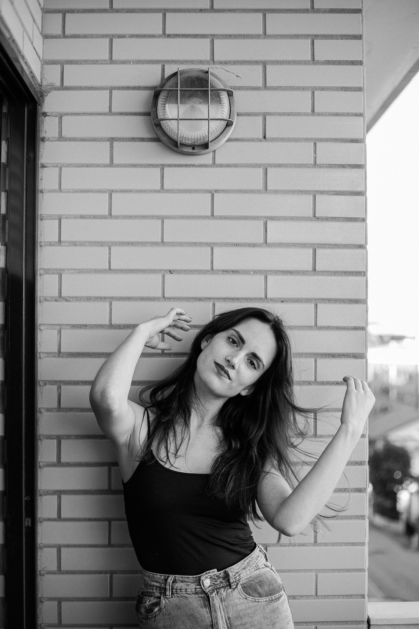 Dramatic monochrome portraits against brick wall showing artistic poses in urban setting.