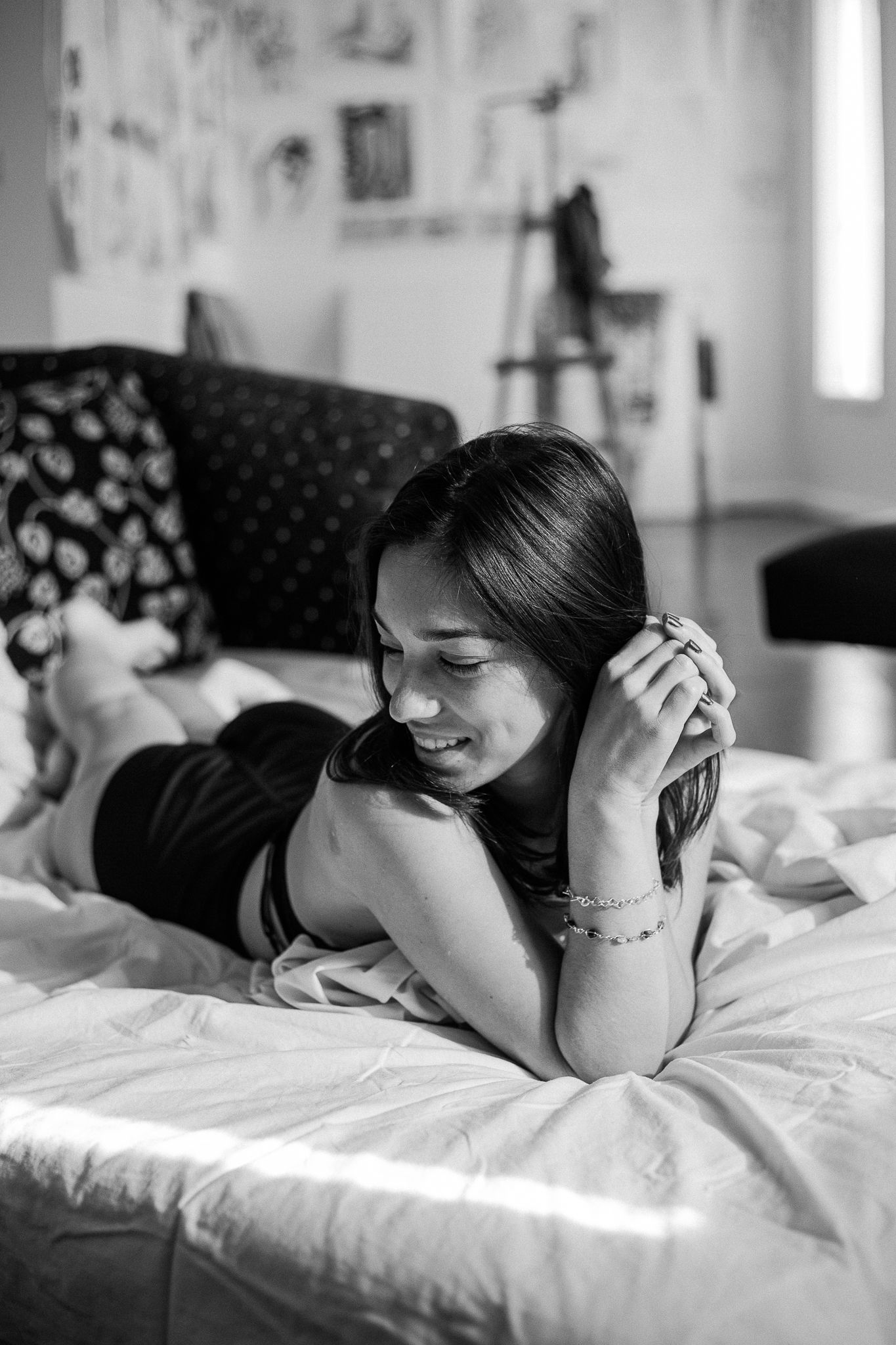 A black and white photo series showing someone lying on a white bed in contemplative poses.