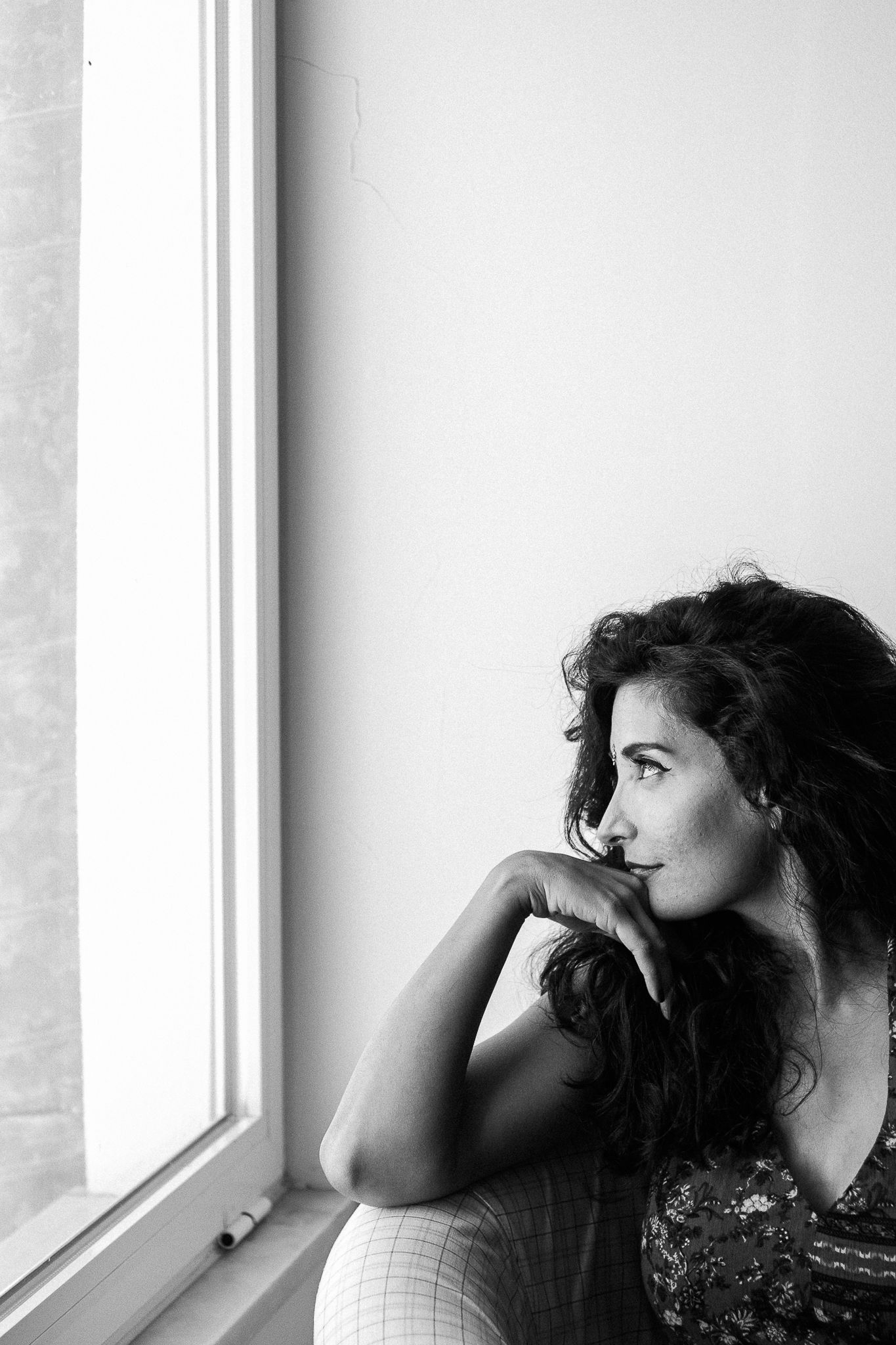 Moody black and white portraits by a window showing contemplative poses.