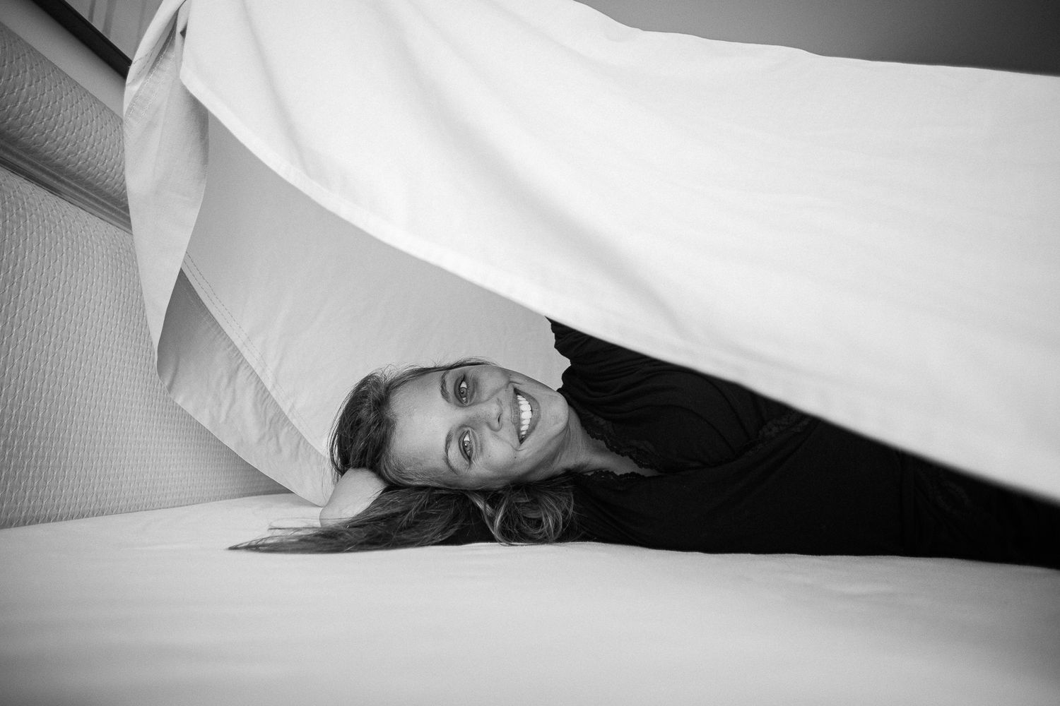 A series of black and white photos showing someone playfully posing under white sheets.