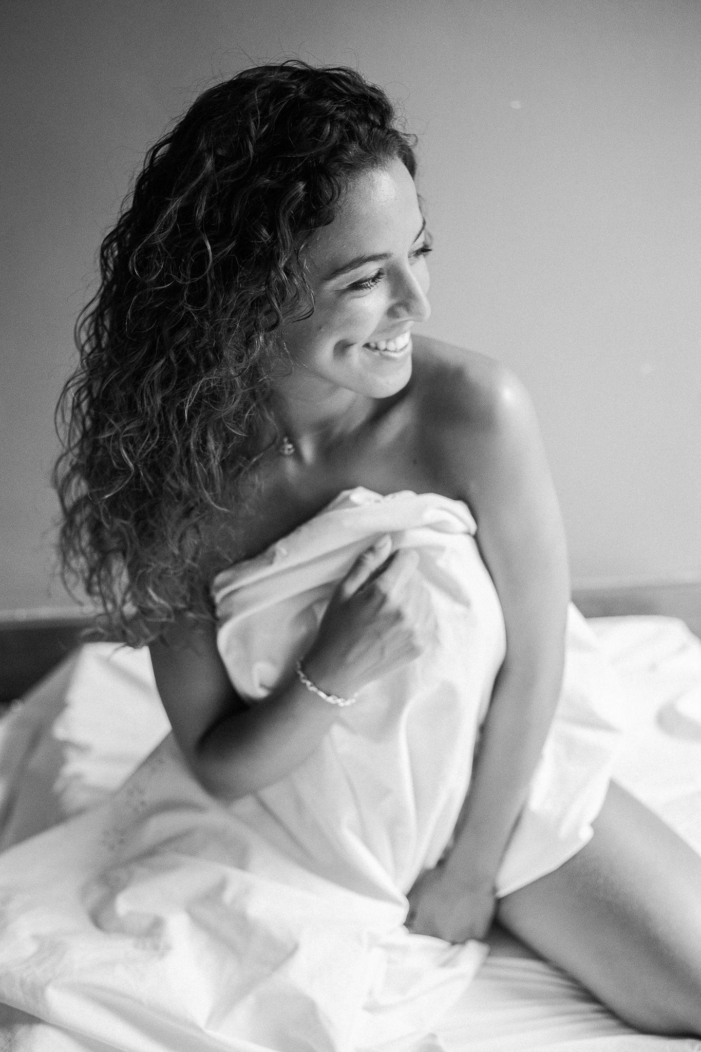 Sensual black and white photo sequence showing relaxed poses with white bedding and natural lighting.