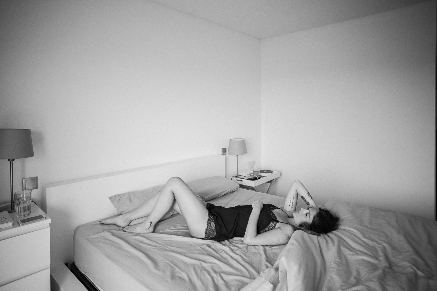Artistic black and white boudoir photo showing a person lying on a bed.
