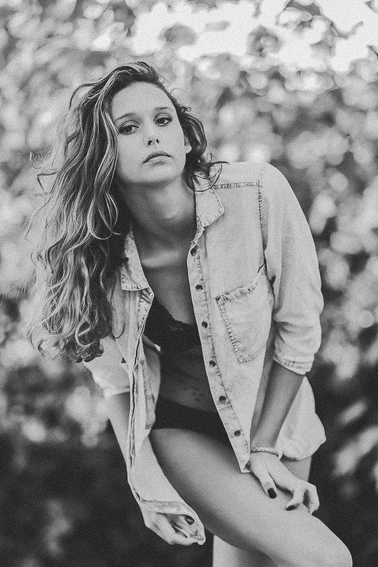 Black and white fashion portraits of a model wearing a denim jacket in an artistic outdoor photoshoot.