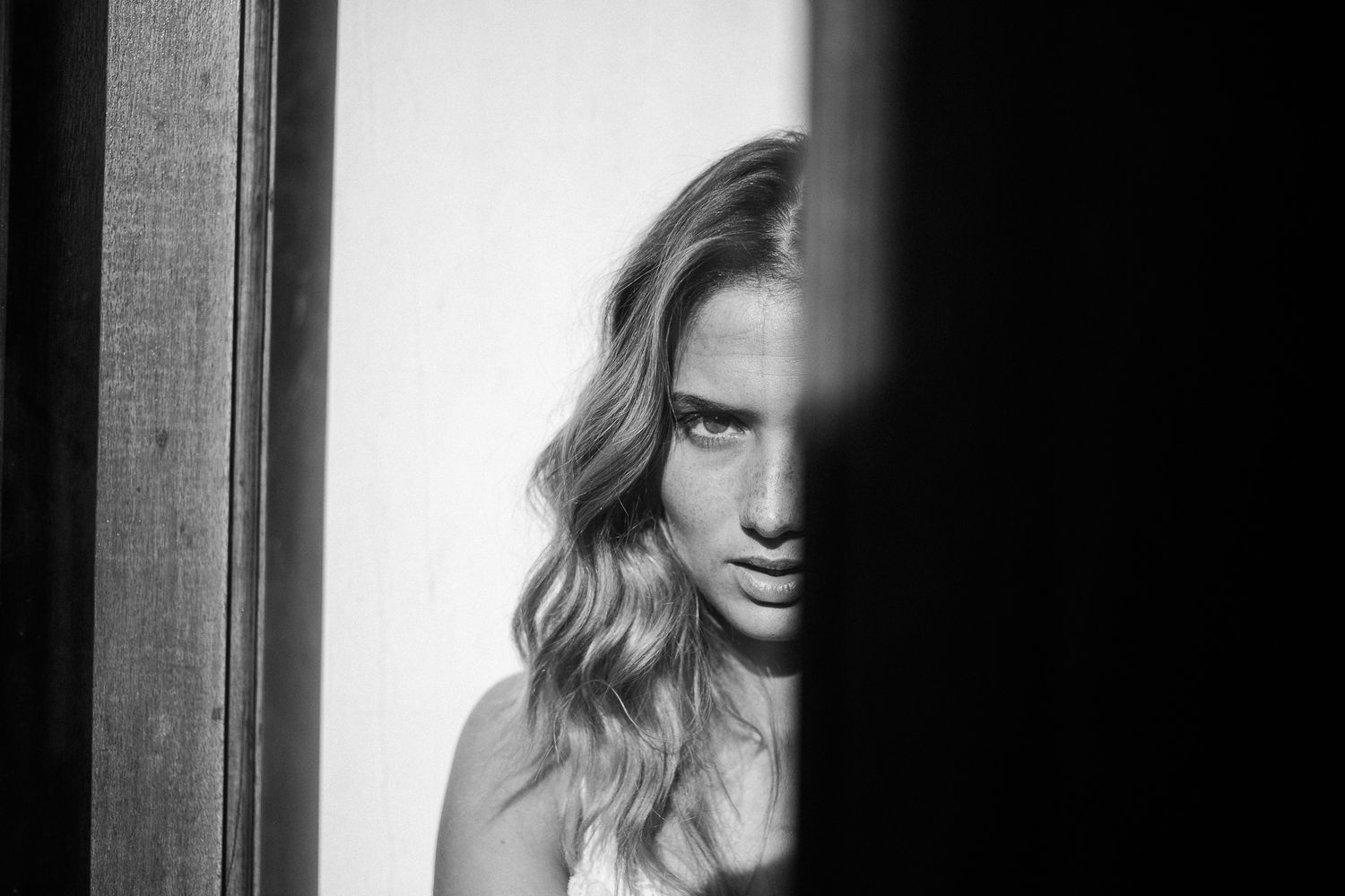 Dramatic black and white portrait split between light and shadow.