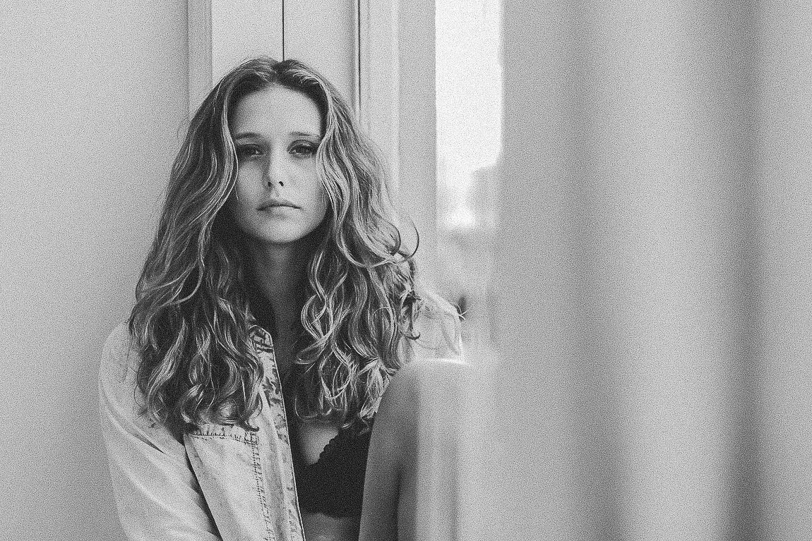 Black and white portrait series of a woman with wavy hair in four different poses against a light background.